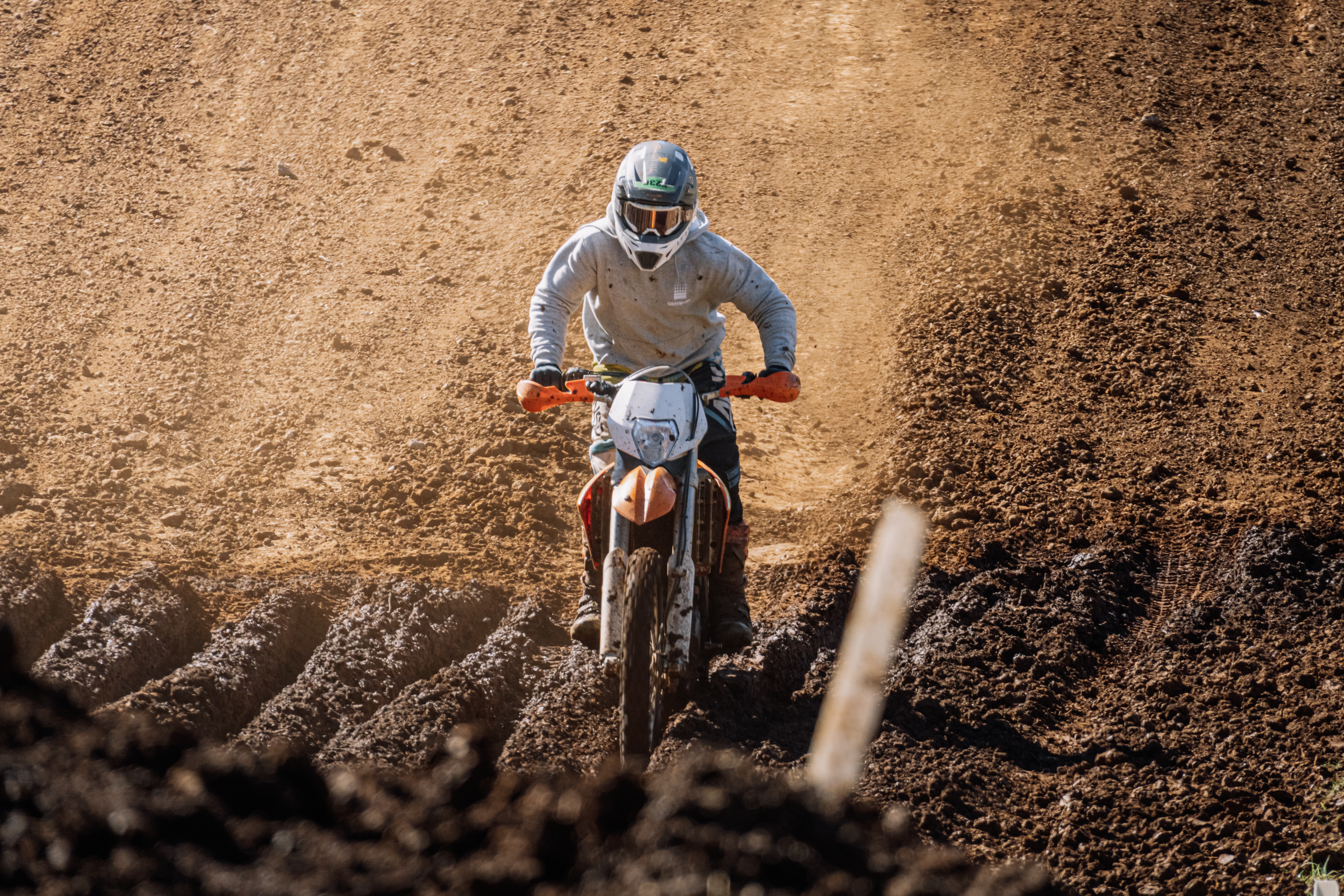 A person riding a dirt bike on a rough, brown, dirt trail.
