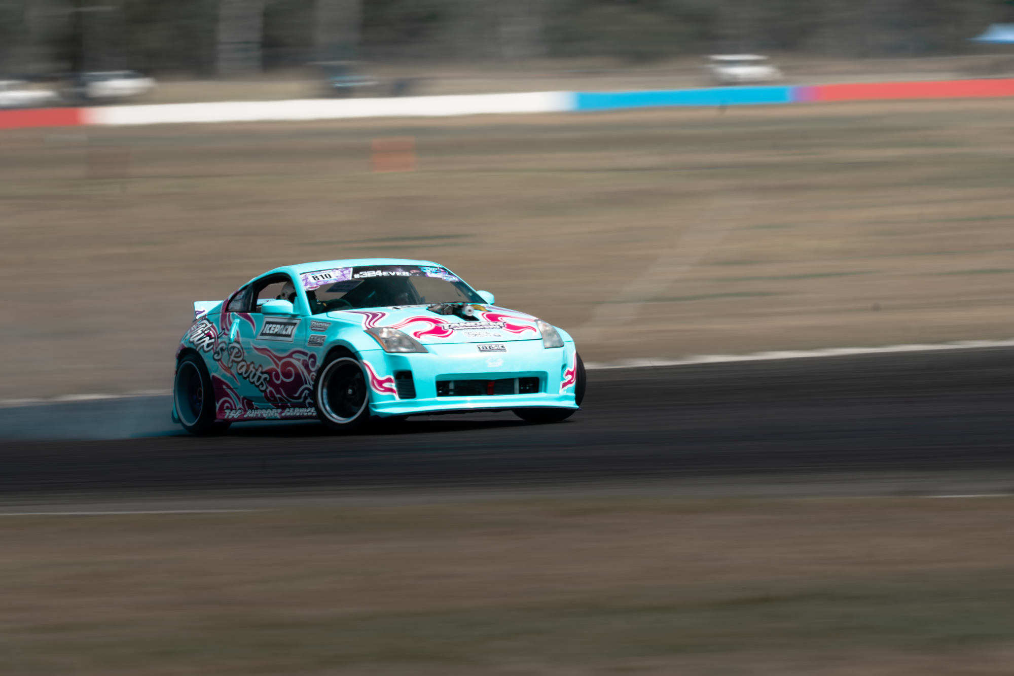 A blue and pink race car speeding on a racetrack, with motion blur in the background.
