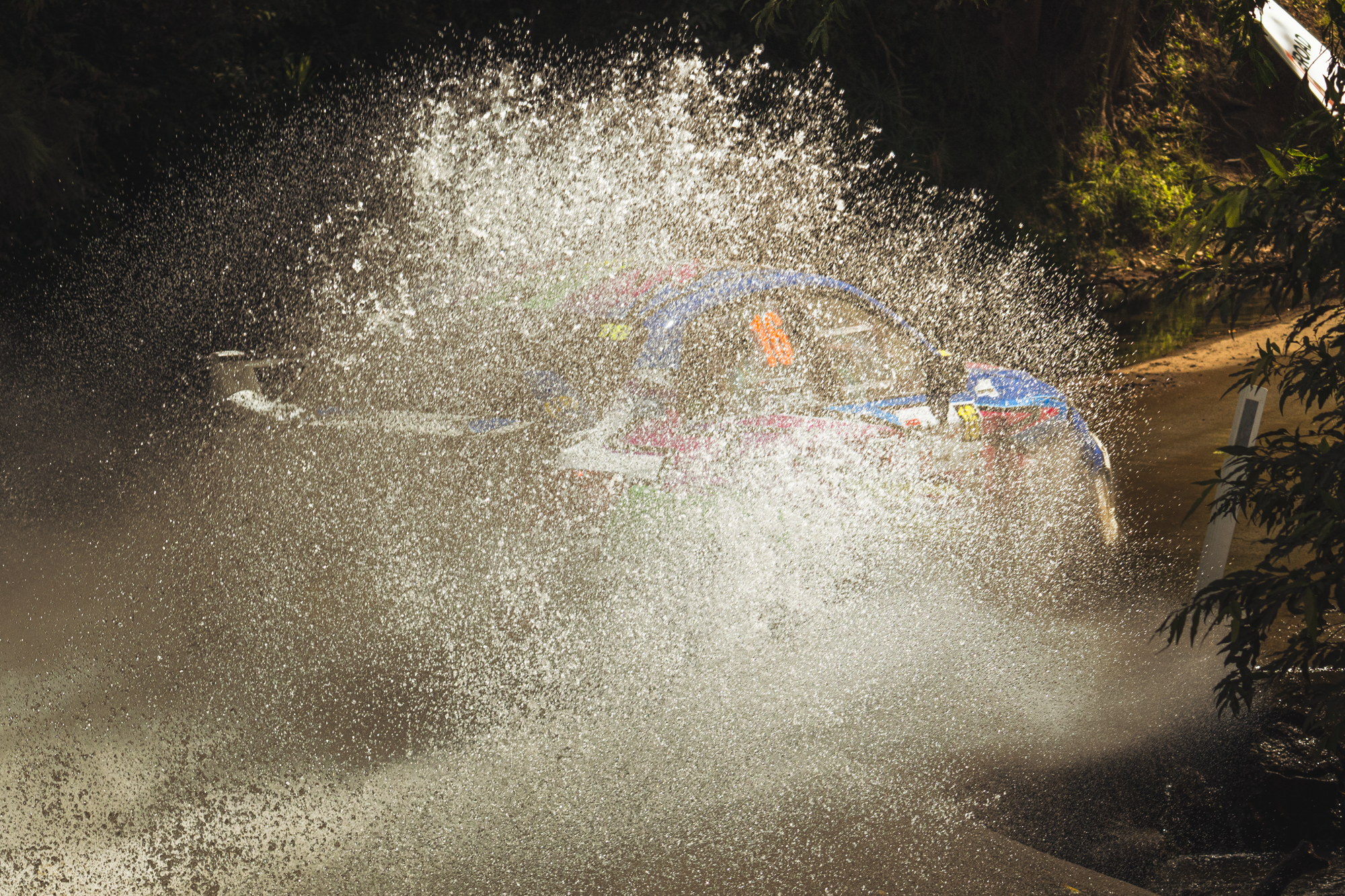 A car crashing into a water fountain, causing a large splash and spray of water.