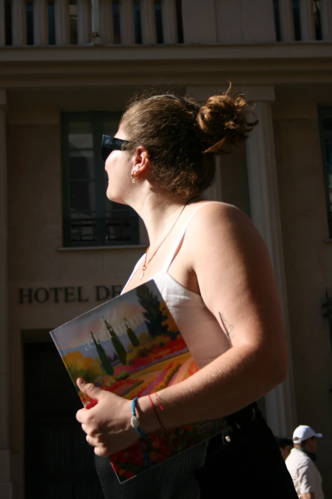 Une femme tient le carnet de mariage Ad Æternam contre elle, debout devant l'Hôtel de Ville de Nice