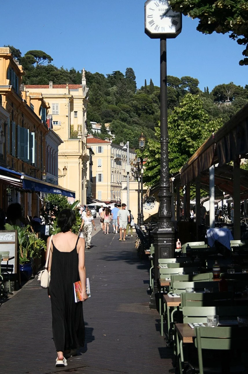 Une femme se promène au Cours Saleya à Nice en tenant le carnet de mariage Ad Æternam à la main