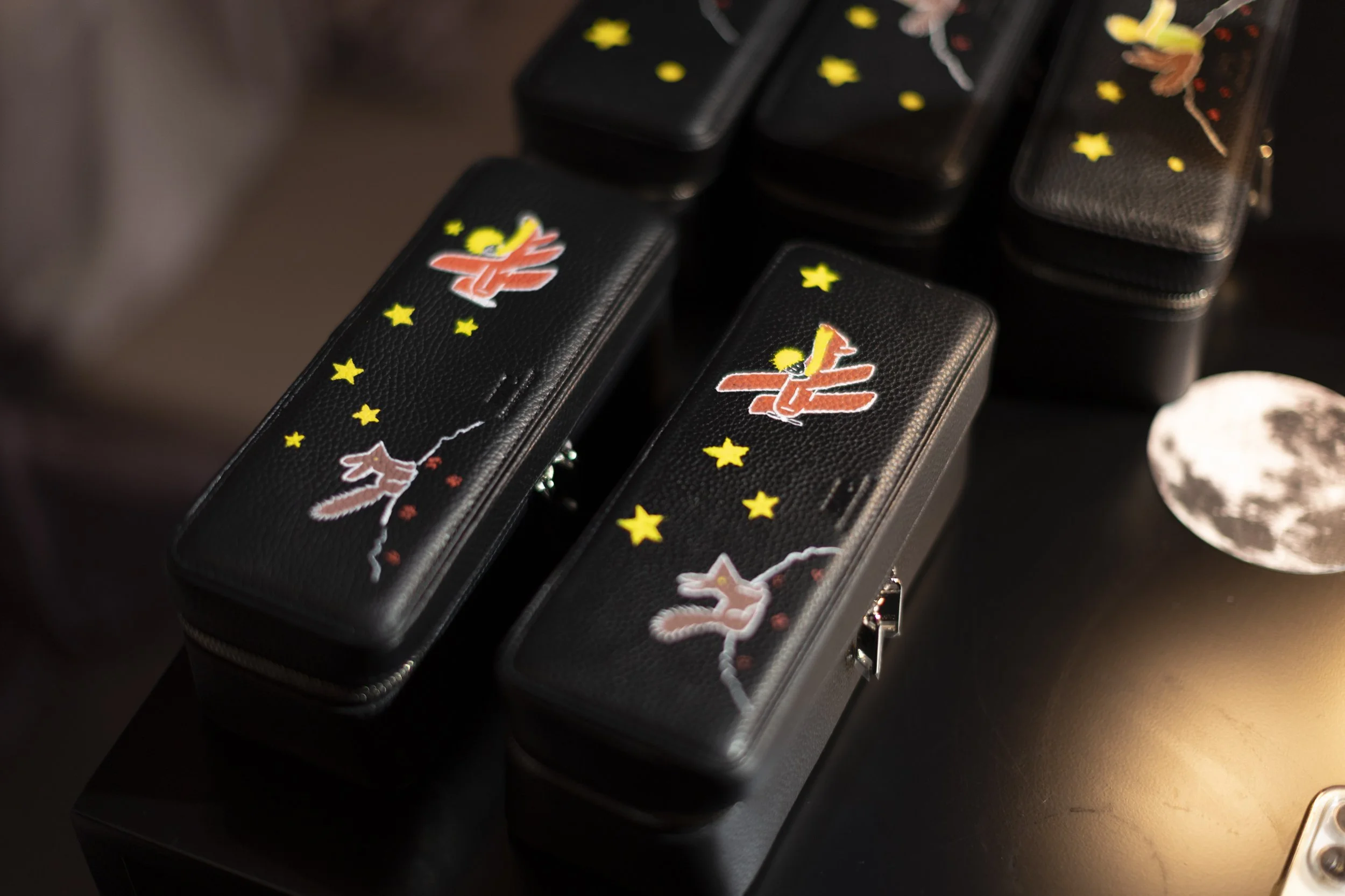 Étuis noirs décorés avec des étoiles, des croissants et des papillons colorés.