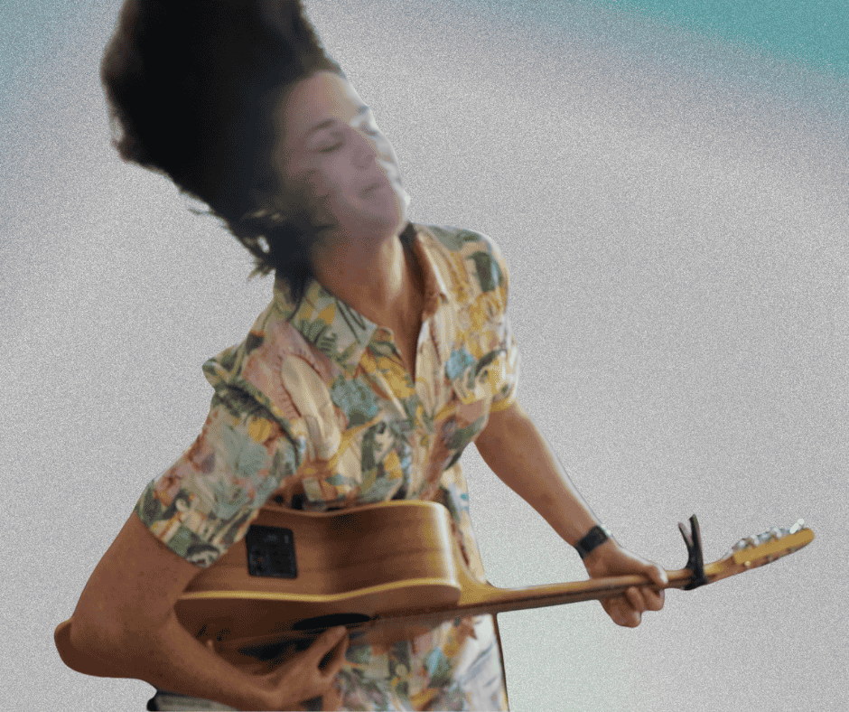 Penny Terry playing an acoustic guitar, with head tilted back and eyes closed, wearing a colorful patterned dress.