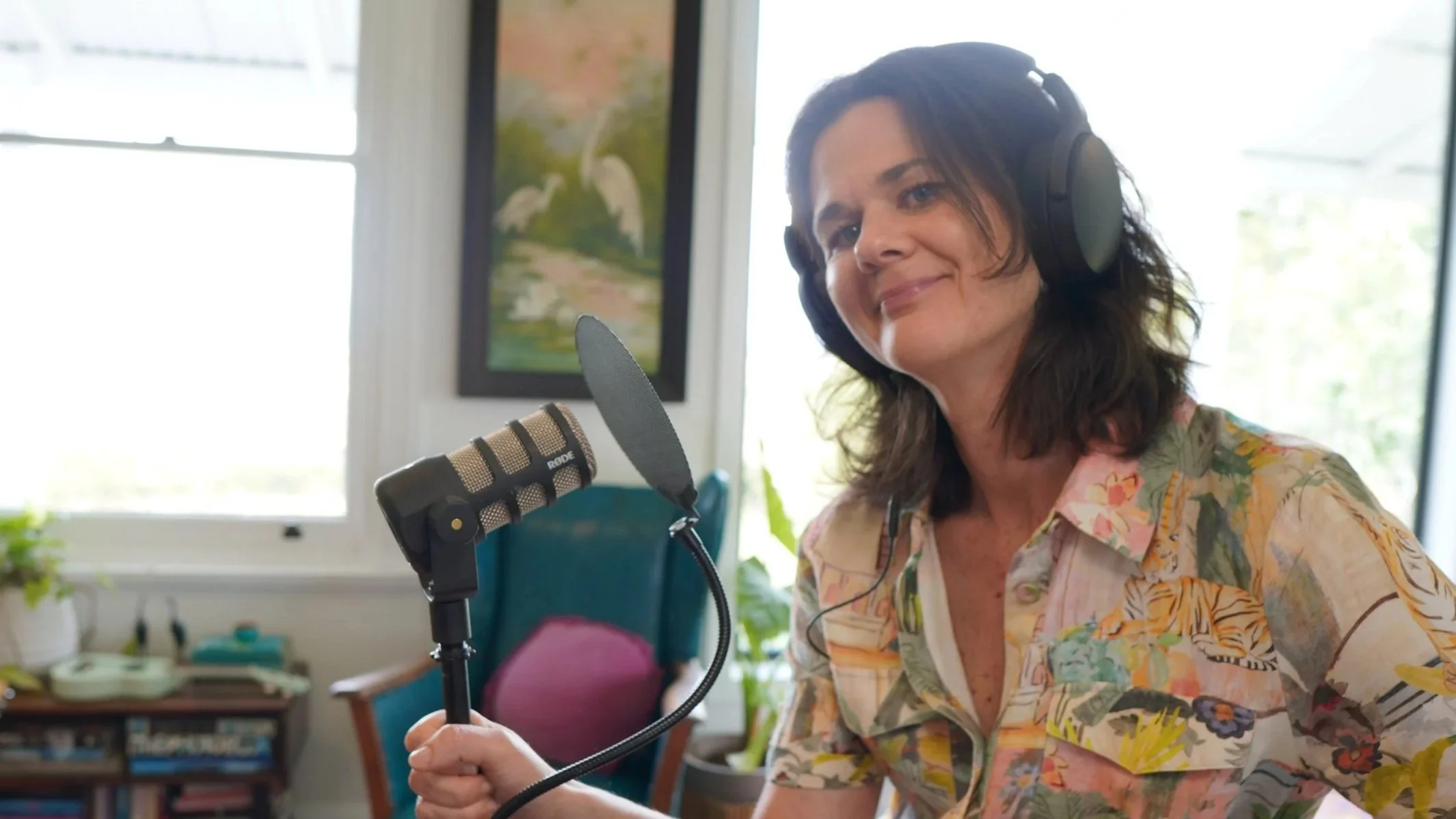 Penny Terry holding a podcast mic with headphones on