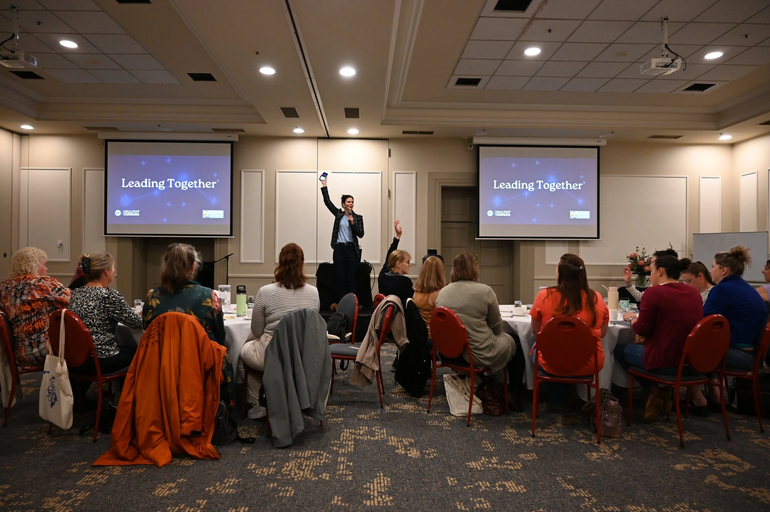 Penny Terry on stage delivering a keynote address about effective leadership communication to a group of female leaders.