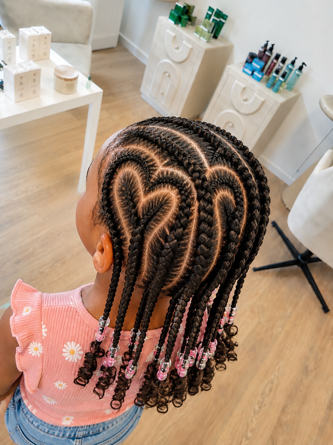 Une jeune fille avec des tresses en épi, décorées avec des perles roses, dans un salon de coiffure, au centre ville de Montauban.