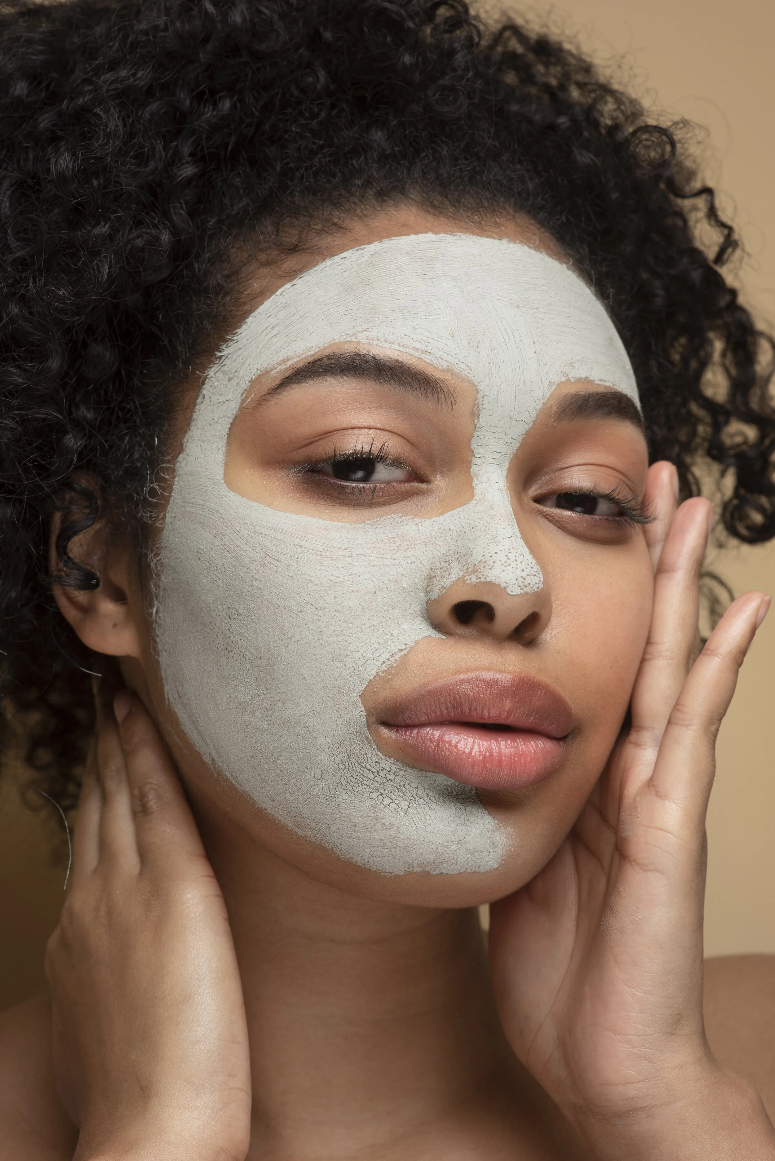 Soin du visage hydratant et purifiant chez DJEDJETRESSES à Montauban. Femme aux cheveux bouclés portant un masque facial pour révéler l'éclat naturel de sa peau et profiter d'un moment de beauté et de bien-être.