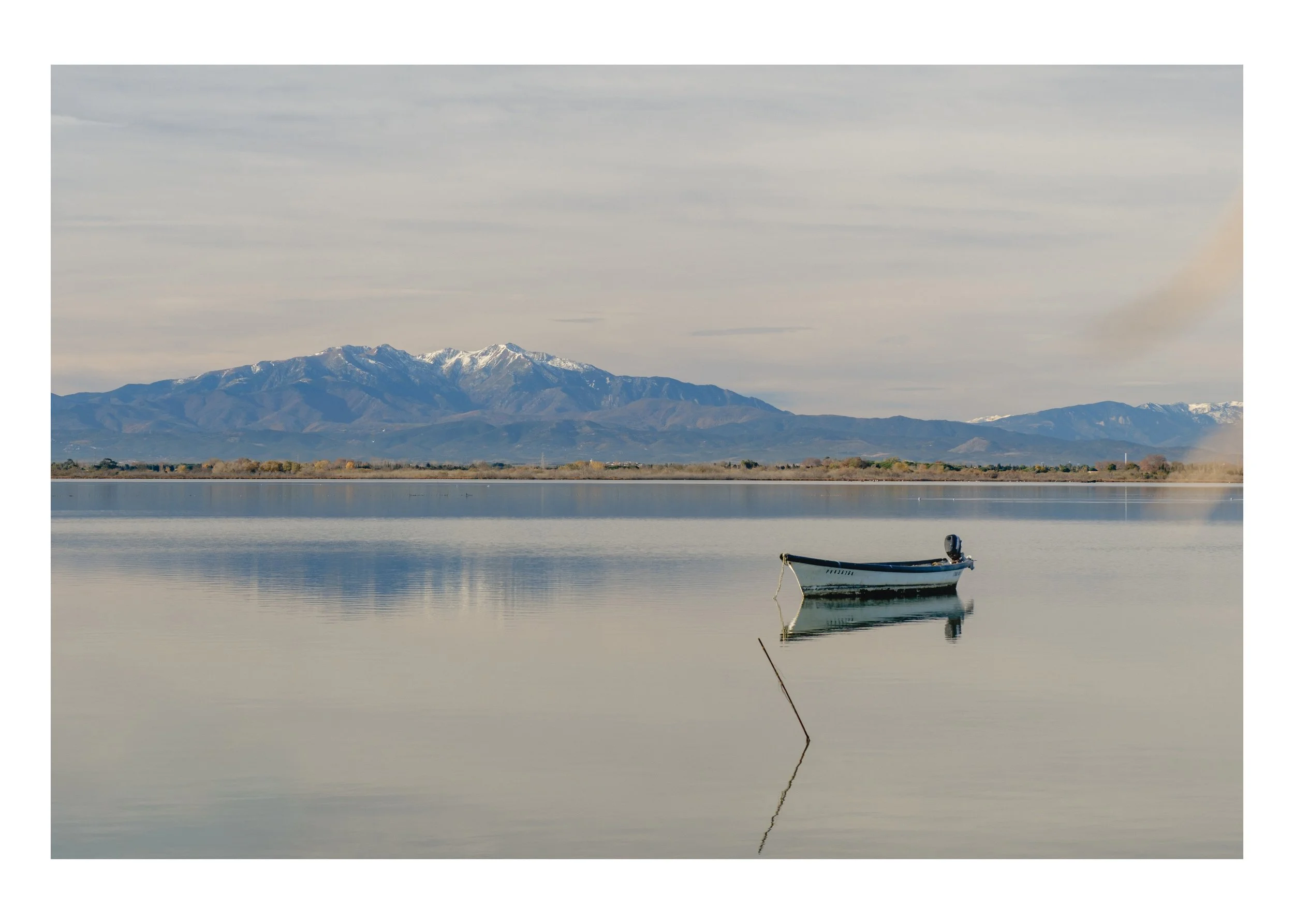 A fishing boat resting on a still lagoon at dusk near Perpignan, France — fine art travel photography print by Frames by Marina