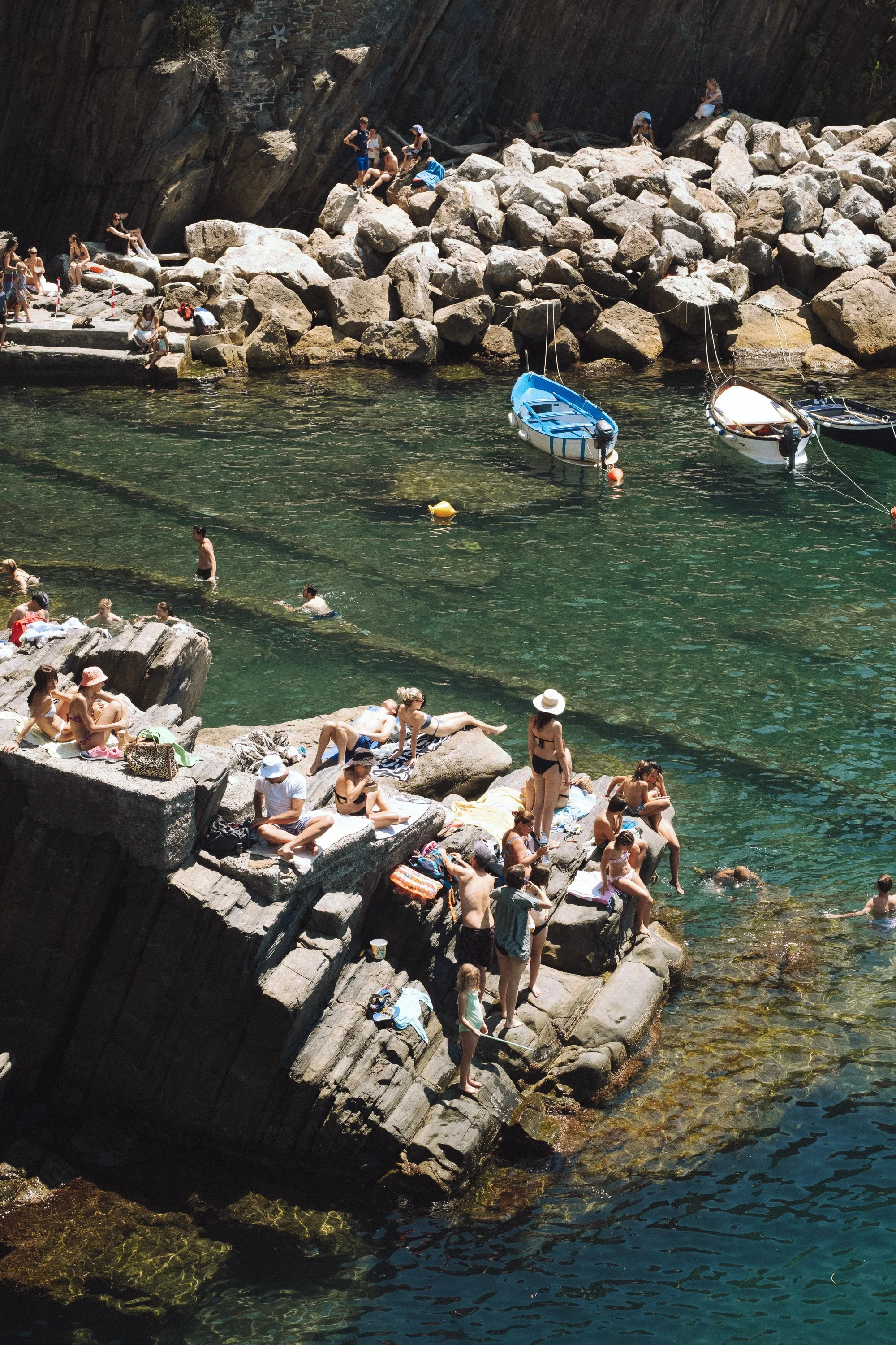 Mediterranean fine art photograph of swimmers along the rocky coastline of Cinque Terre. A vibrant Italian summer wall print.