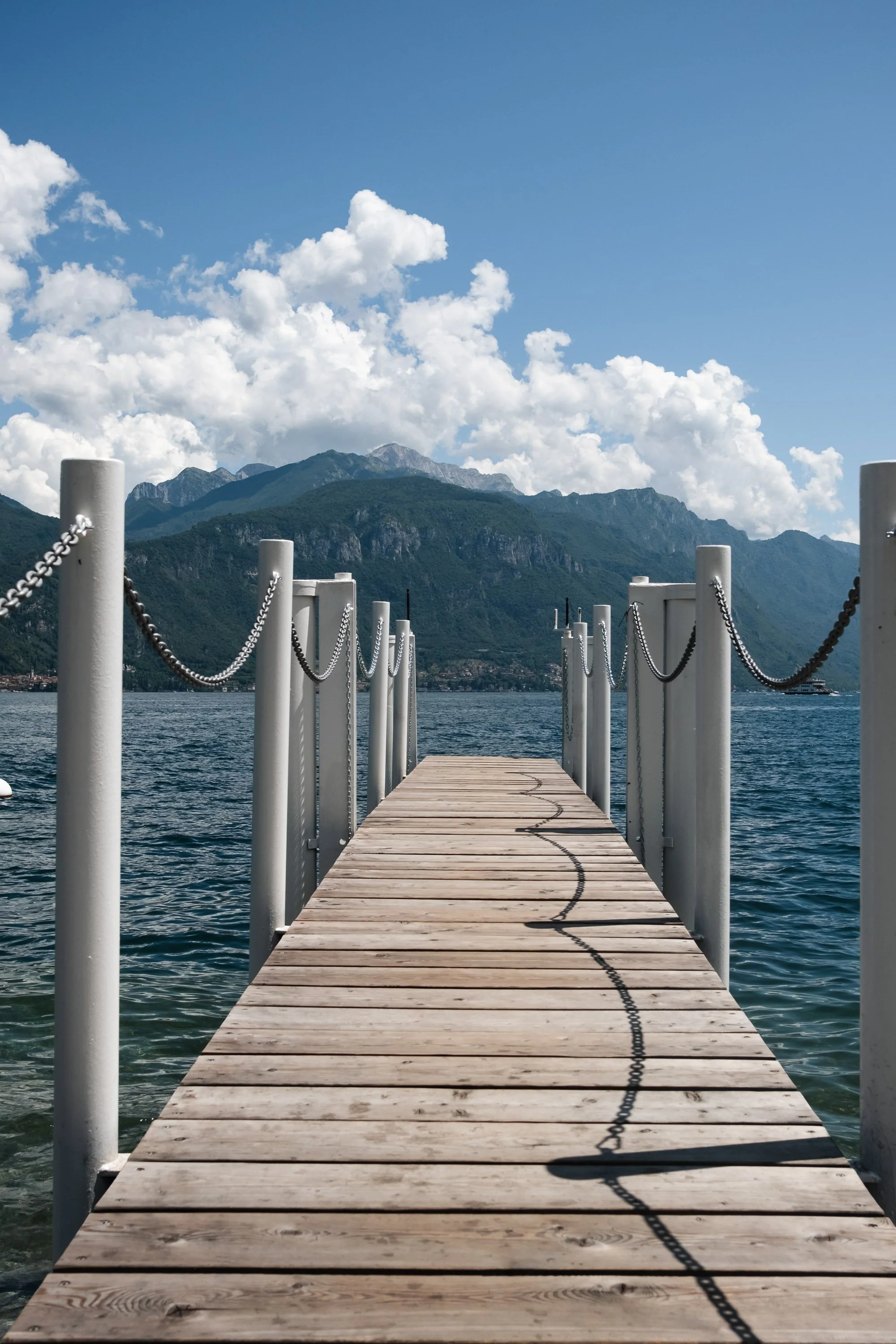 Minimal lake landscape print featuring a wooden pier extending toward alpine mountains under blue skies. Calm, modern nature wall art.
