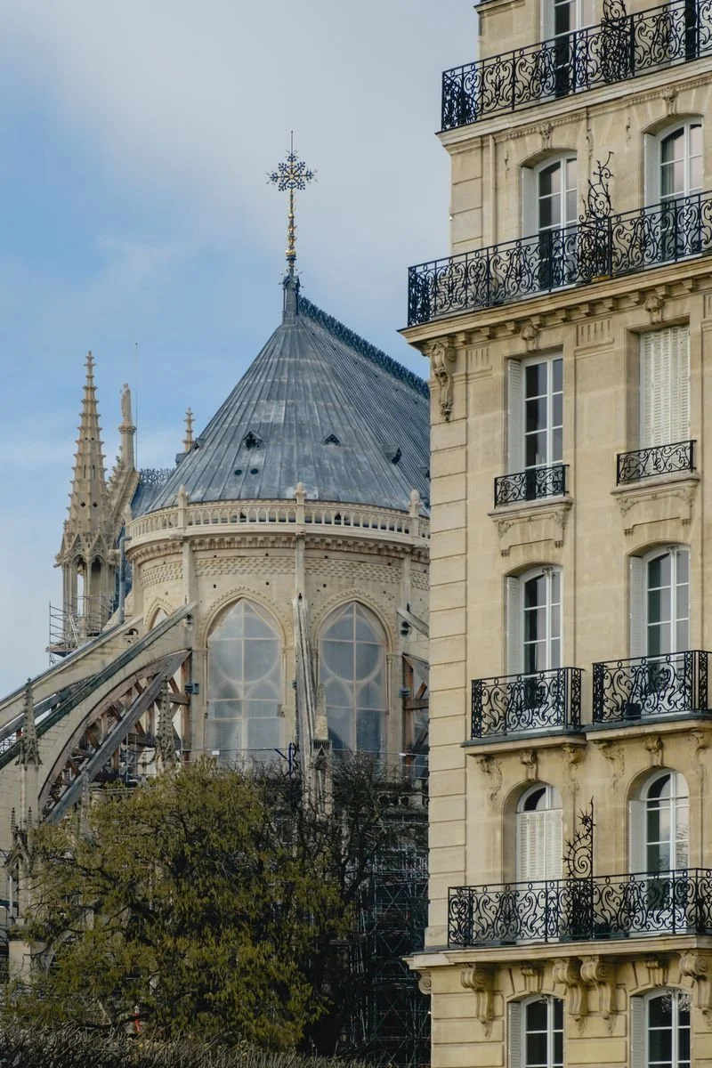 Notre-Dame's rebuilt apse and spire scaffolding beside a Haussmannian apartment facade