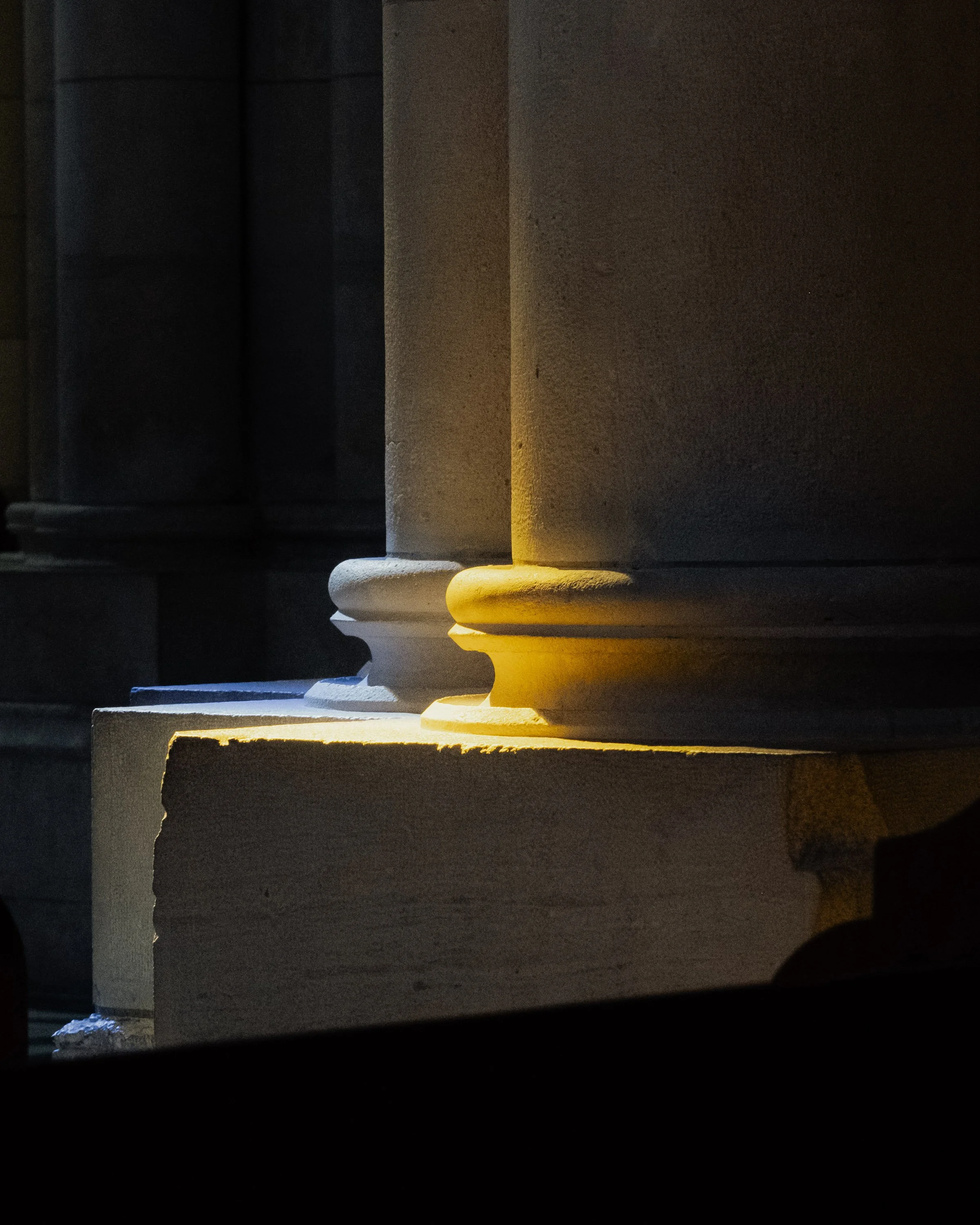 Close-up view of stone columns with sunlight casting shadows on them.