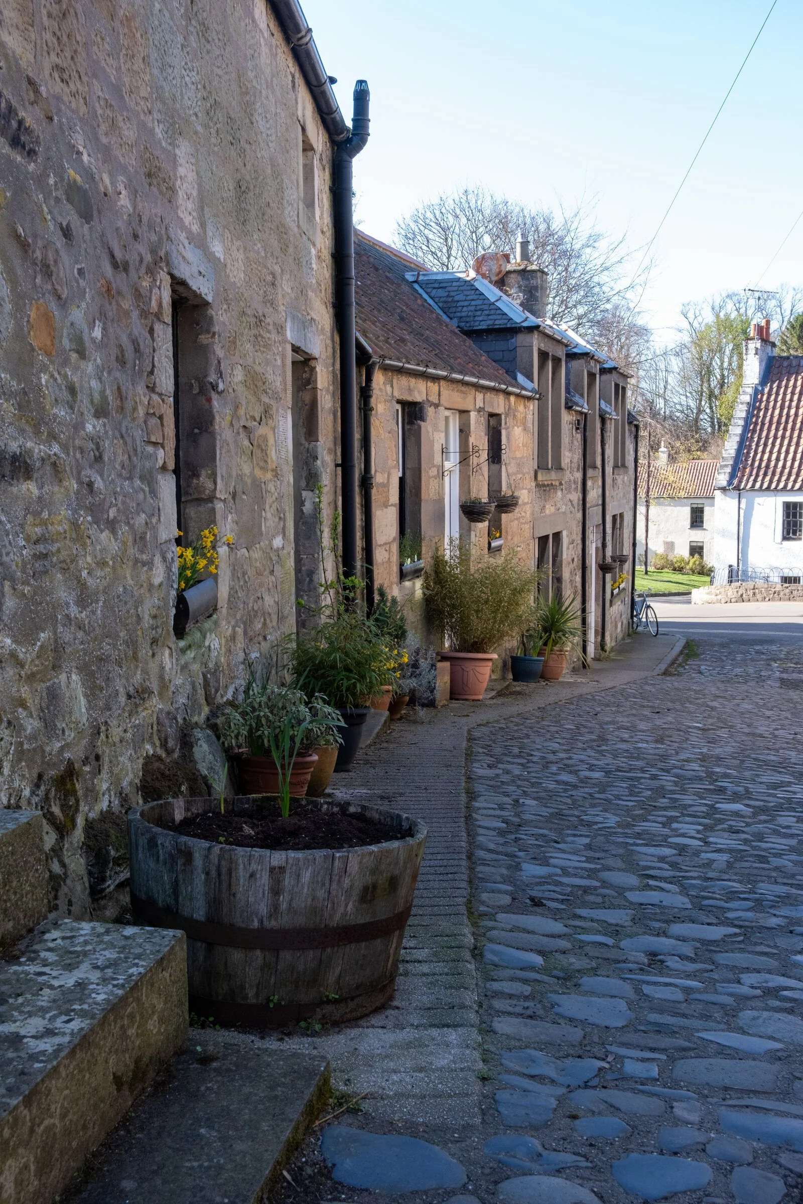 A narrow cobbled lane winds between stone cottages in a Fife coastal village