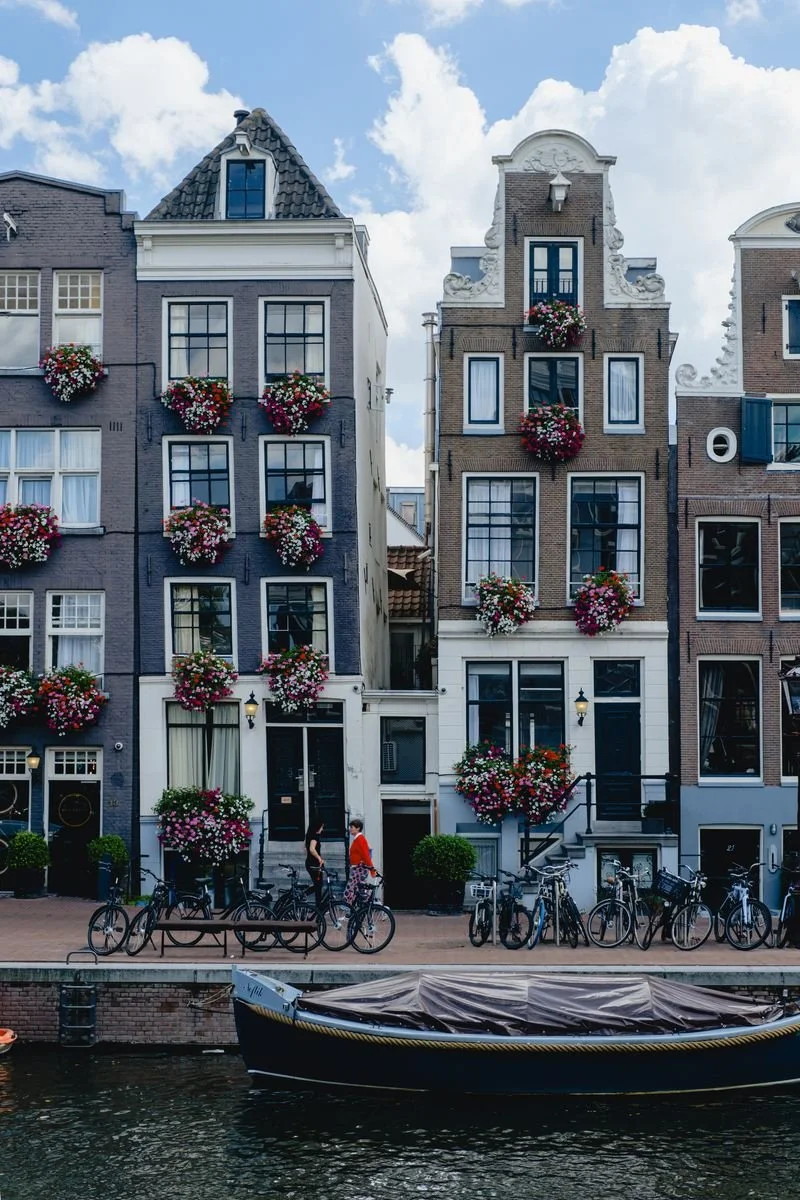 Gabled Amsterdam canal houses dressed in hanging flower boxes