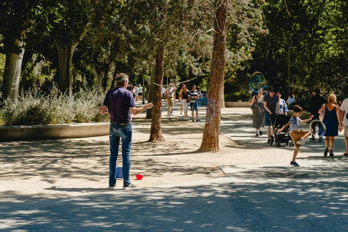 A street performer blowing giant bubbles for a crowd of children in El Retiro