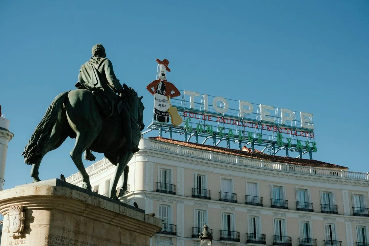 Equestrian statue of Carlos III with the illuminated Tio Pepe sign behind, Puerta del Sol