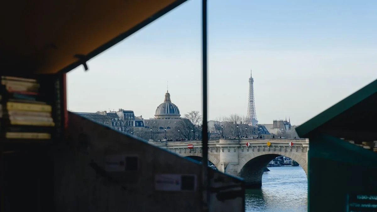The Institut de France dome and the Eiffel Tower seen through the open shelf of a riverside bookstall