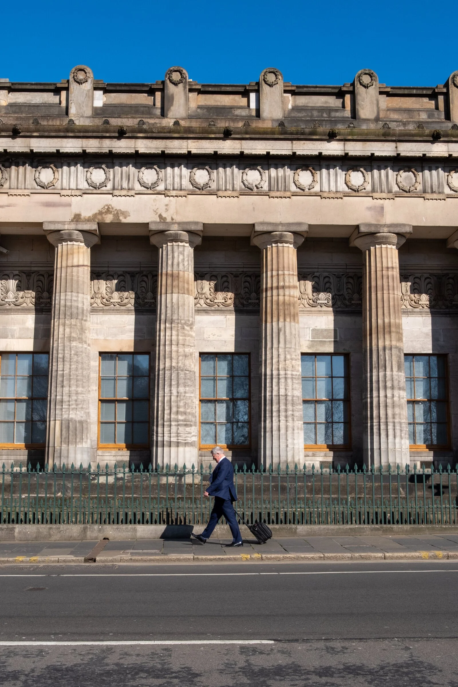 A pedestrian walks past towering neoclassical stone columns in Edinburgh on a quiet morning