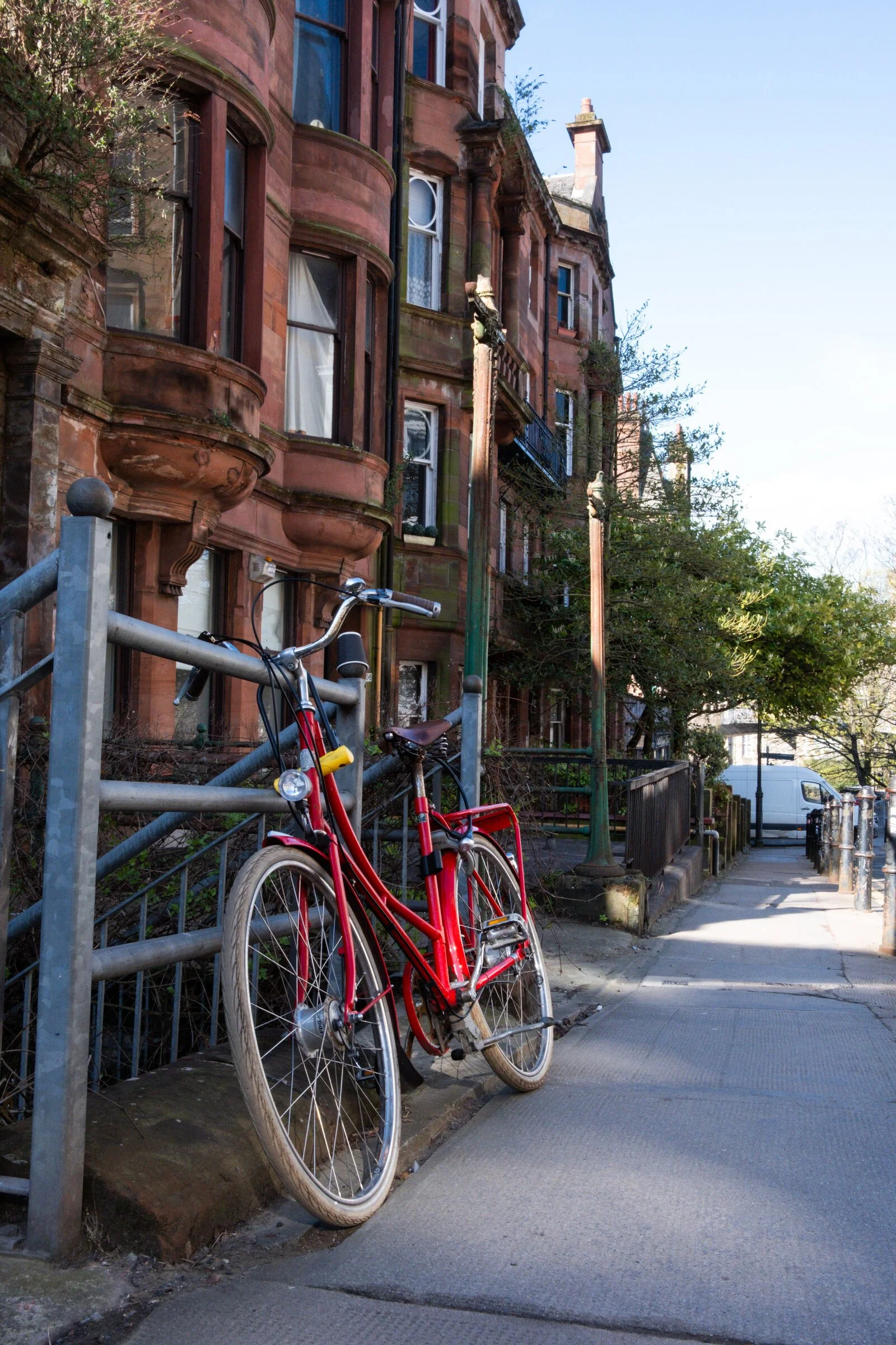 A red bicycle leans against a red sandstone tenement building in Glasgow