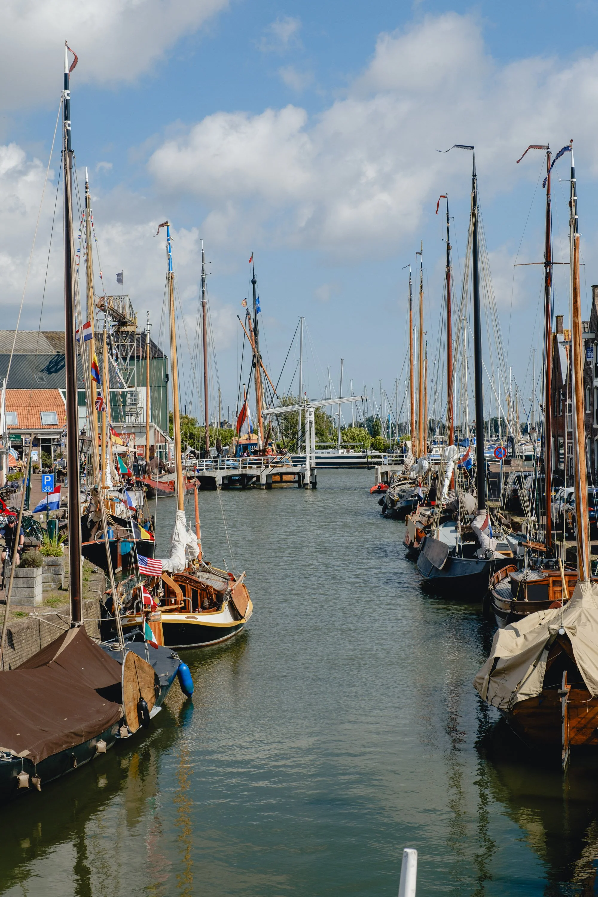 A marina with sailboats docked on both sides of a waterway, under a partly cloudy sky.
