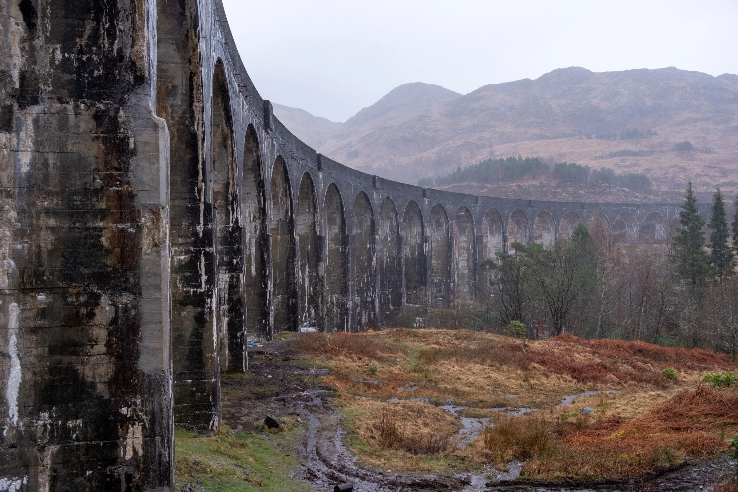 The Glenfinnan Viaduct's stone arches curve away into Highland mist