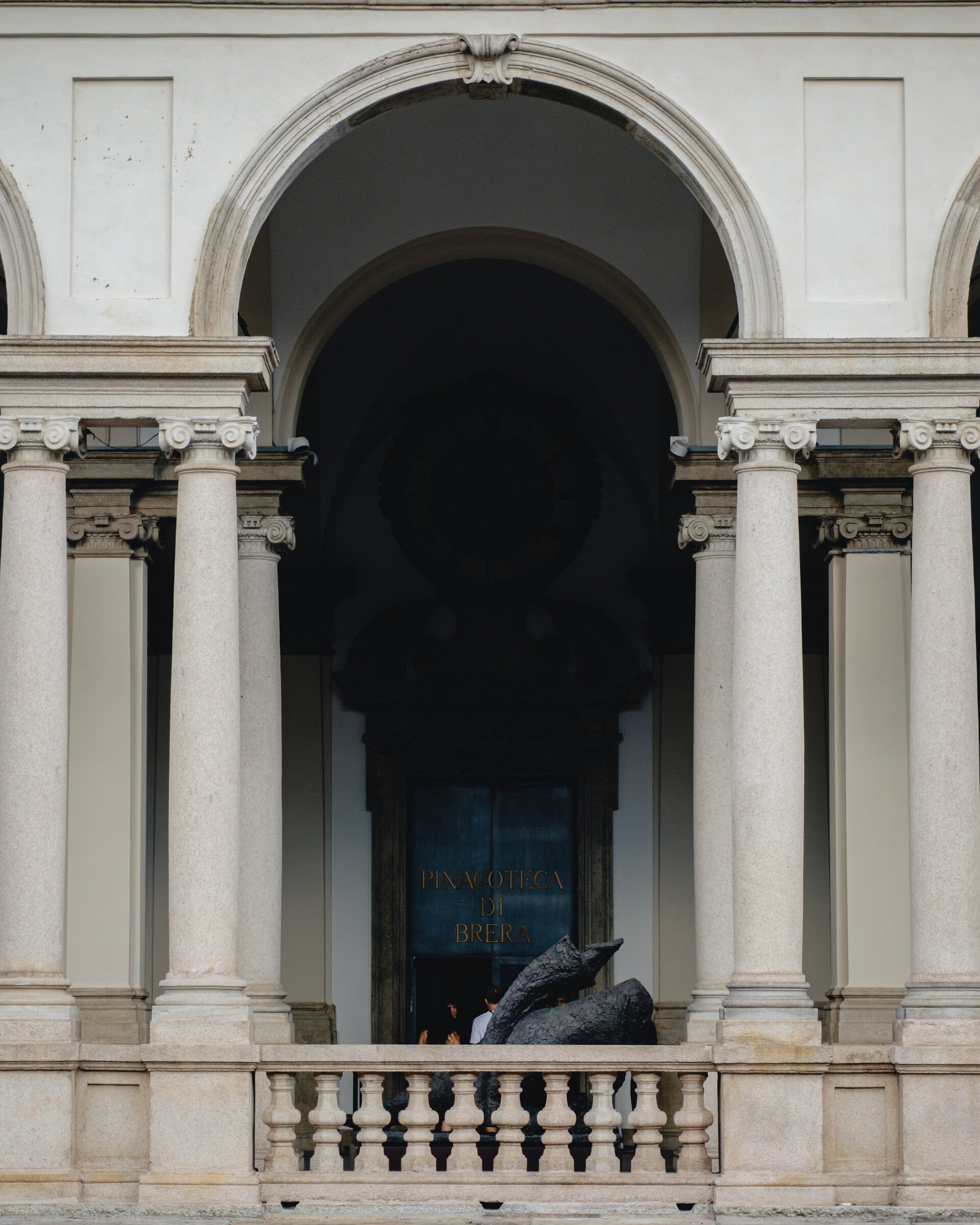 Ionic columns frame the arched doorway of the Pinacoteca di Brera museum, its name lettered above the entrance