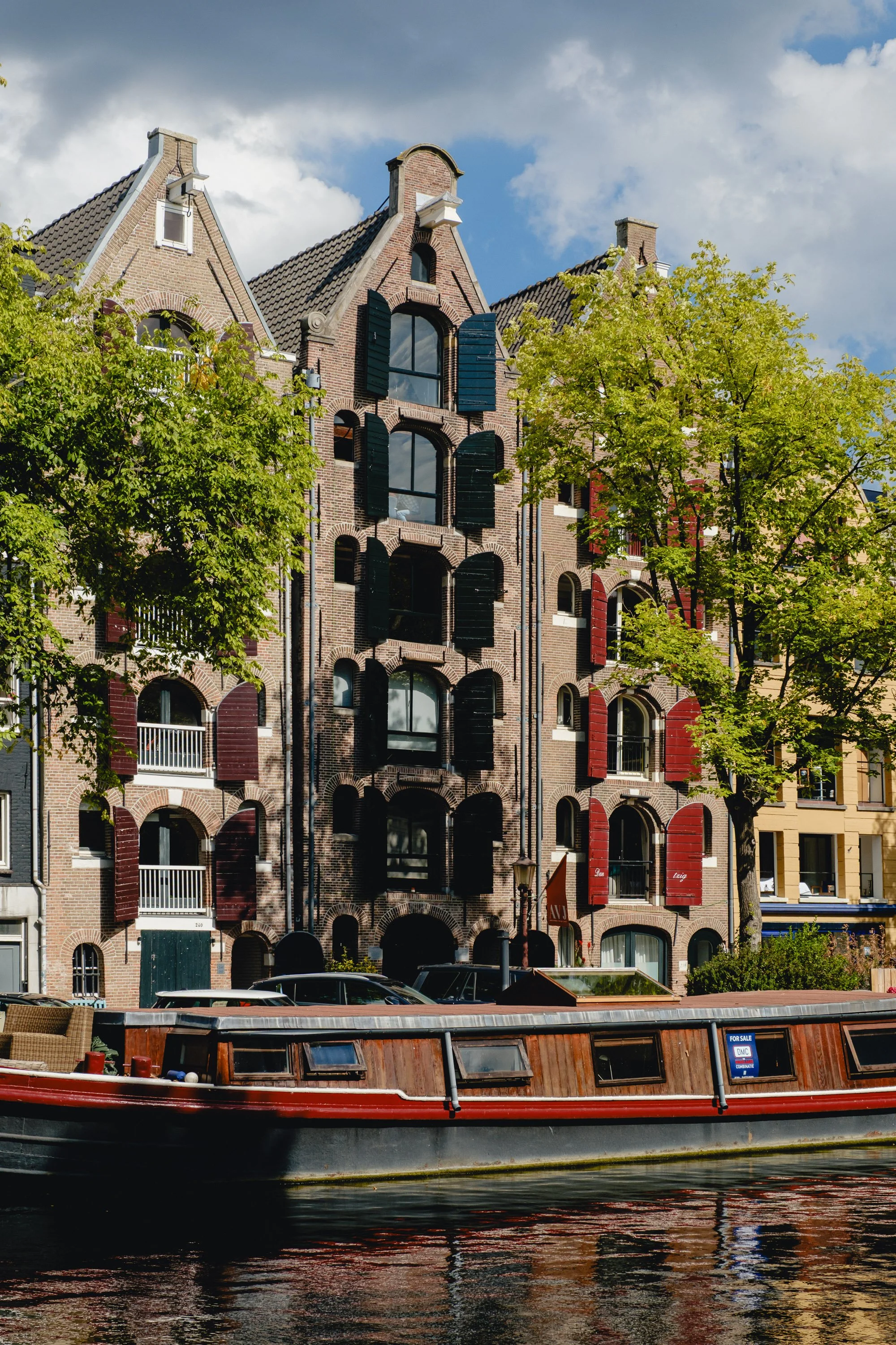 Colorful traditional Dutch-style canal houses with decorative shutters and a boat on the canal in Amsterdam.