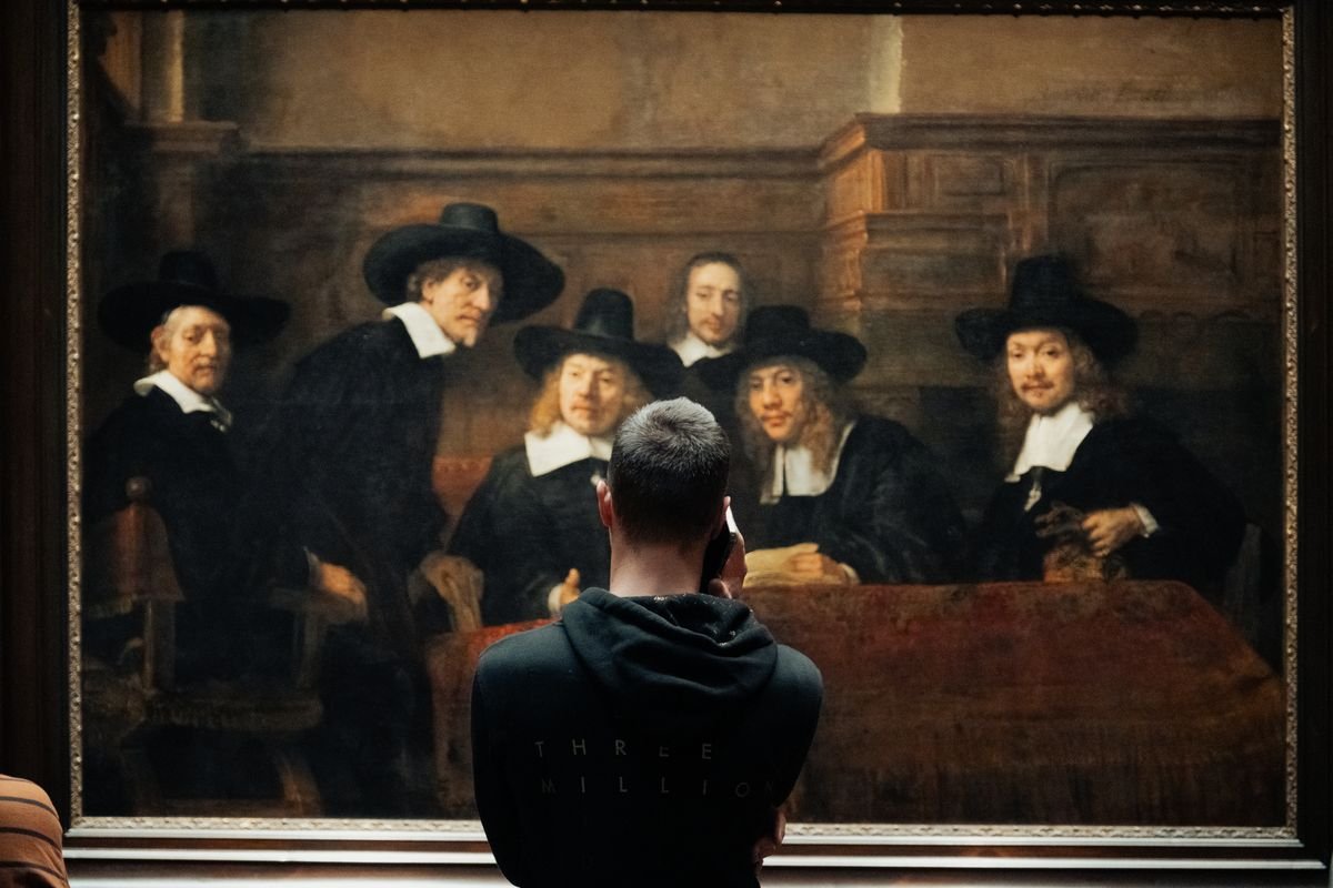 A visitor photographs Rembrandt's The Syndics on his phone at the Rijksmuseum