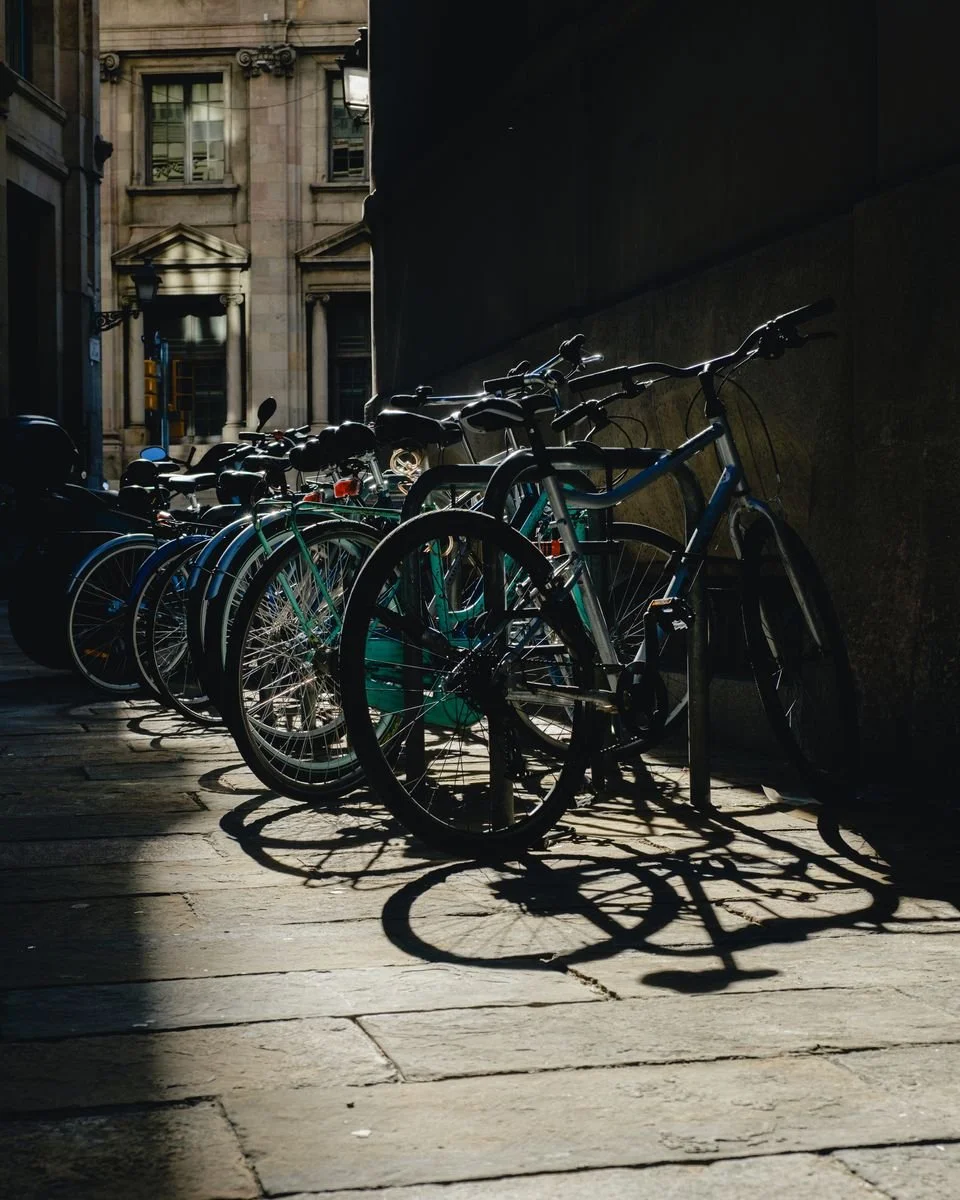 Bicycles parked in a sunlit alley cast long shadows across the cobblestones
