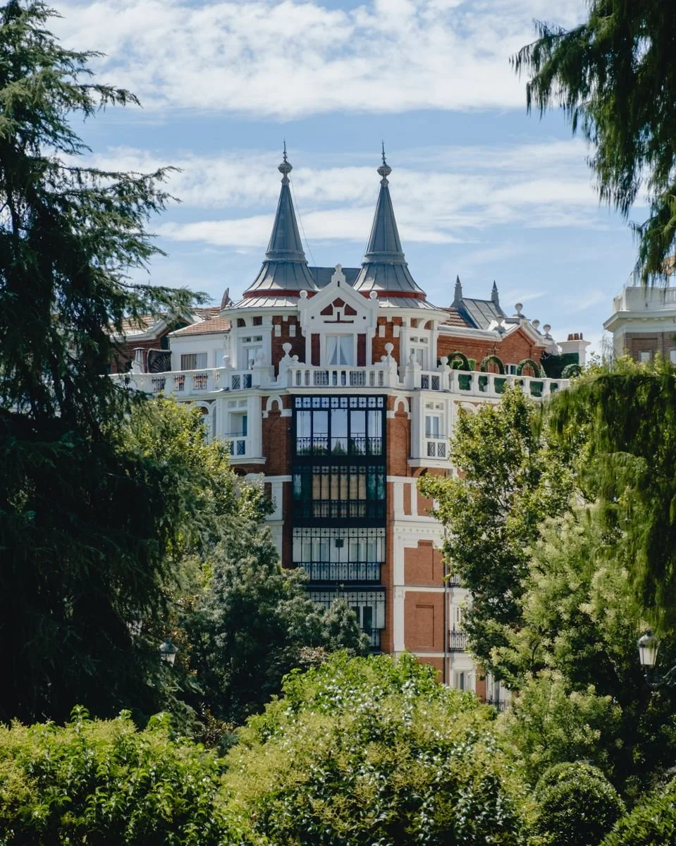 A red-brick mansion with twin turrets glimpsed through the trees near El Retiro