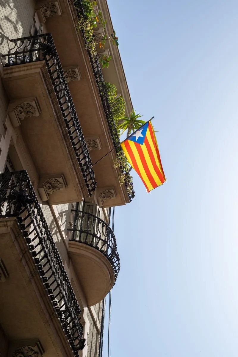 A Catalan independence flag hangs from wrought-iron balconies against a clear sky