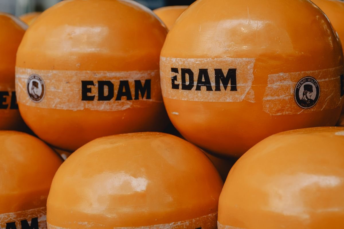 Wheels of Edam cheese, stacked and labeled at a market stall