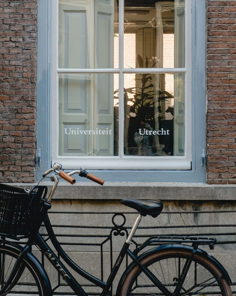 A bicycle rests beneath a University Utrecht window