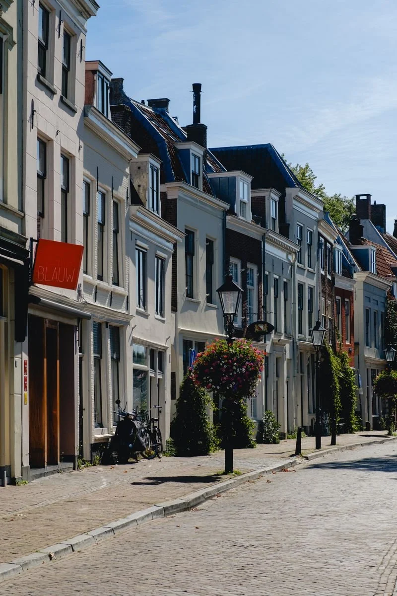 A quiet street lined with gabled houses and hanging flower baskets