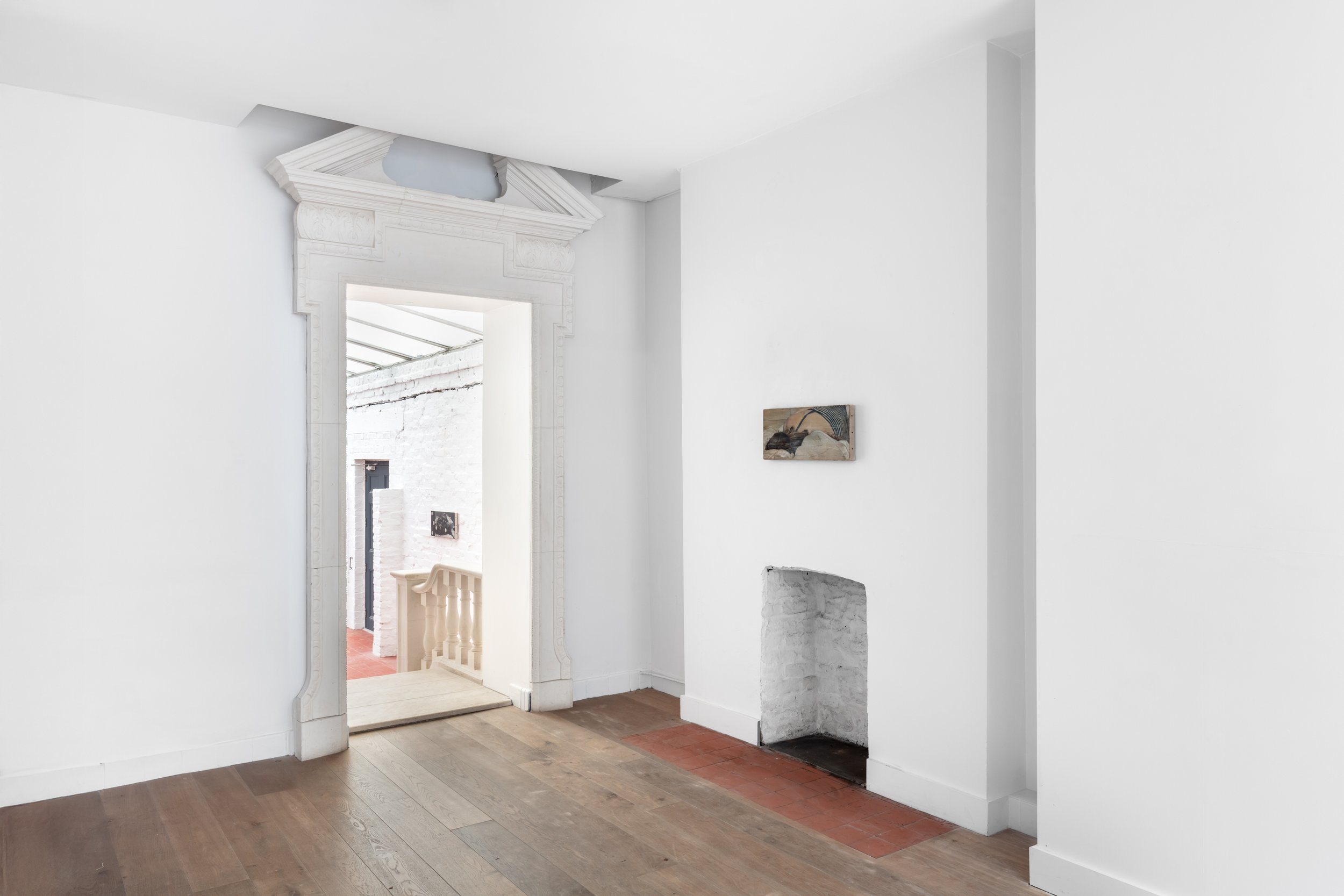 Image of a gallery space with a portrait hanging on the white wall. 