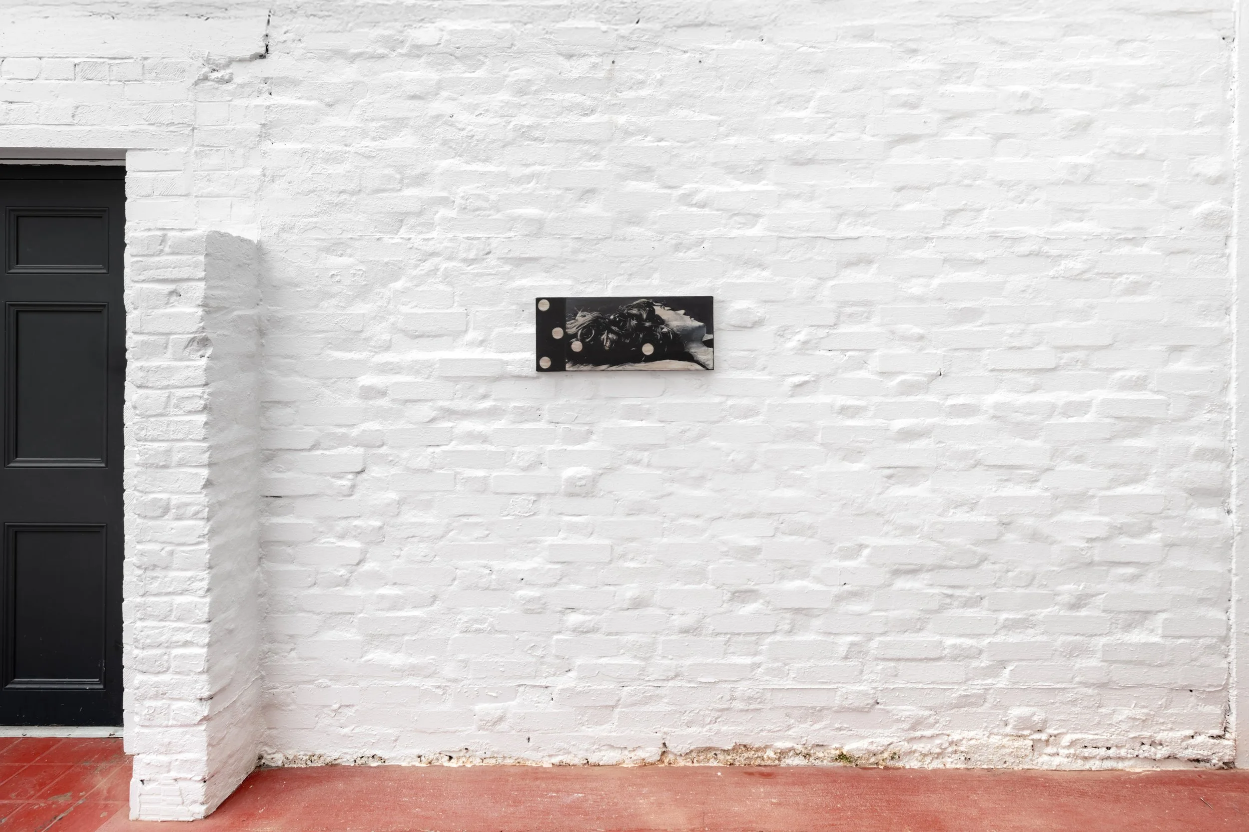 Image of a gallery space with a black and white portrait hanging on the white wall. 