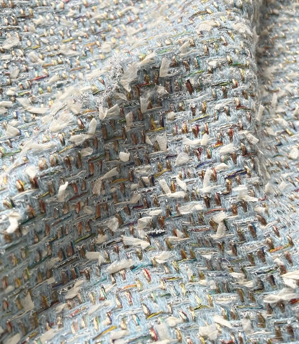 Close-up of a woven textile with interlaced colored threads and fabric torn in a corner.