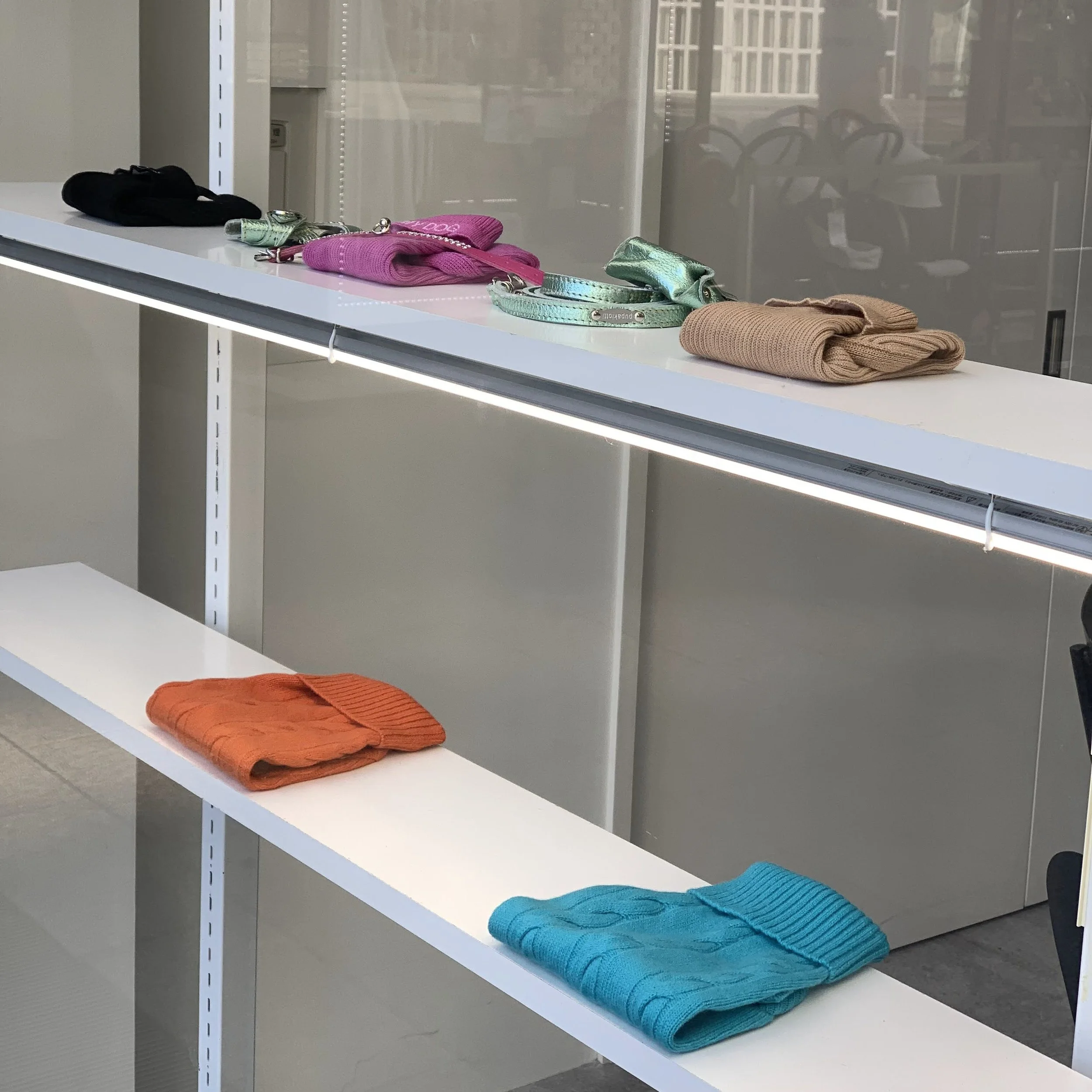 Colorful folded scarves and gloves on display shelves in a retail store.