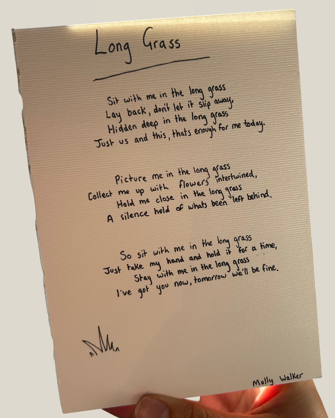 A handwritten poem titled 'Long Grass' on a beige paper, signed by Molly Walker, with the poem about sitting in and appreciating the long grass, accompanied by a small doodle at the bottom left corner.