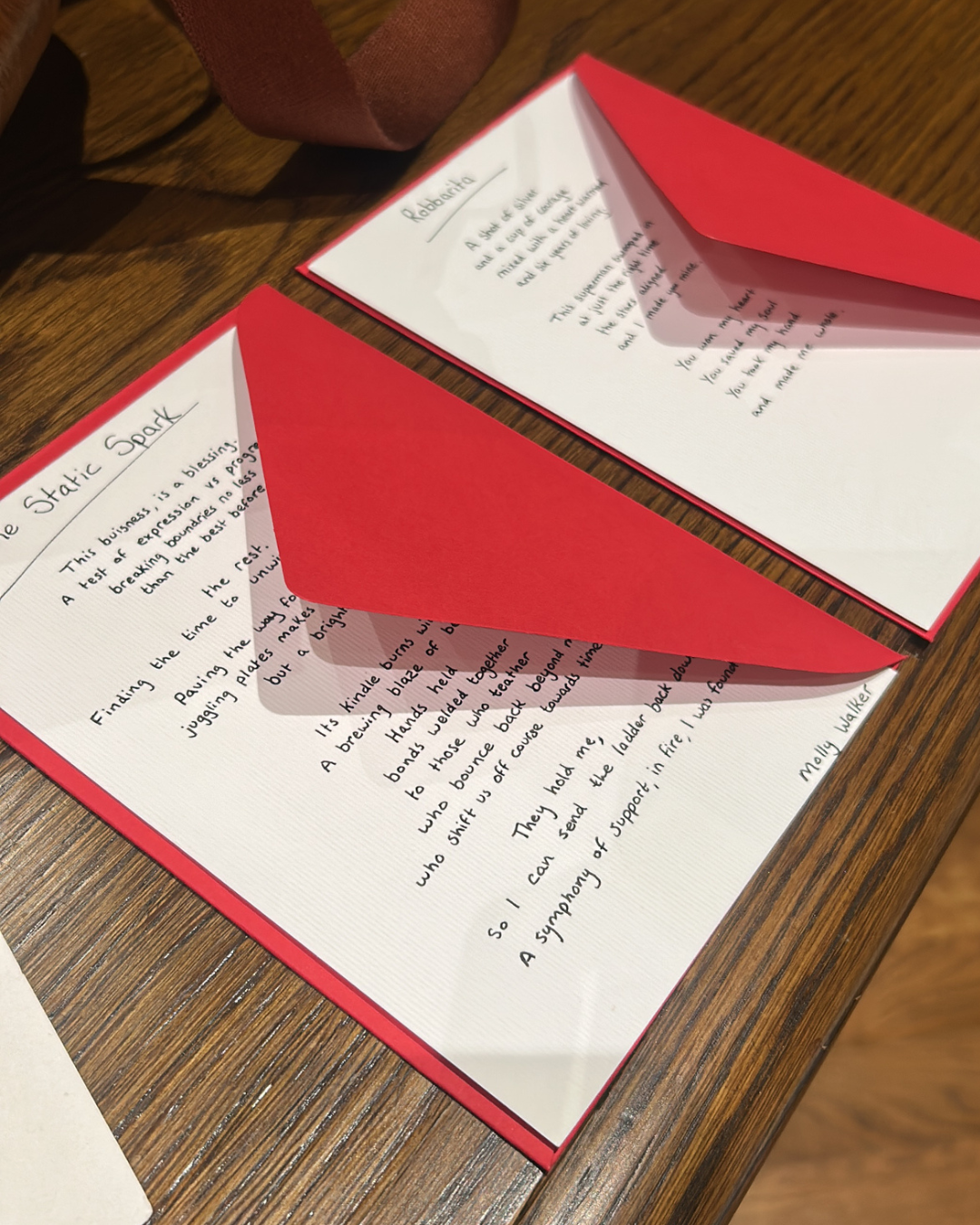 Open red greeting cards with handwritten messages on a wooden table.