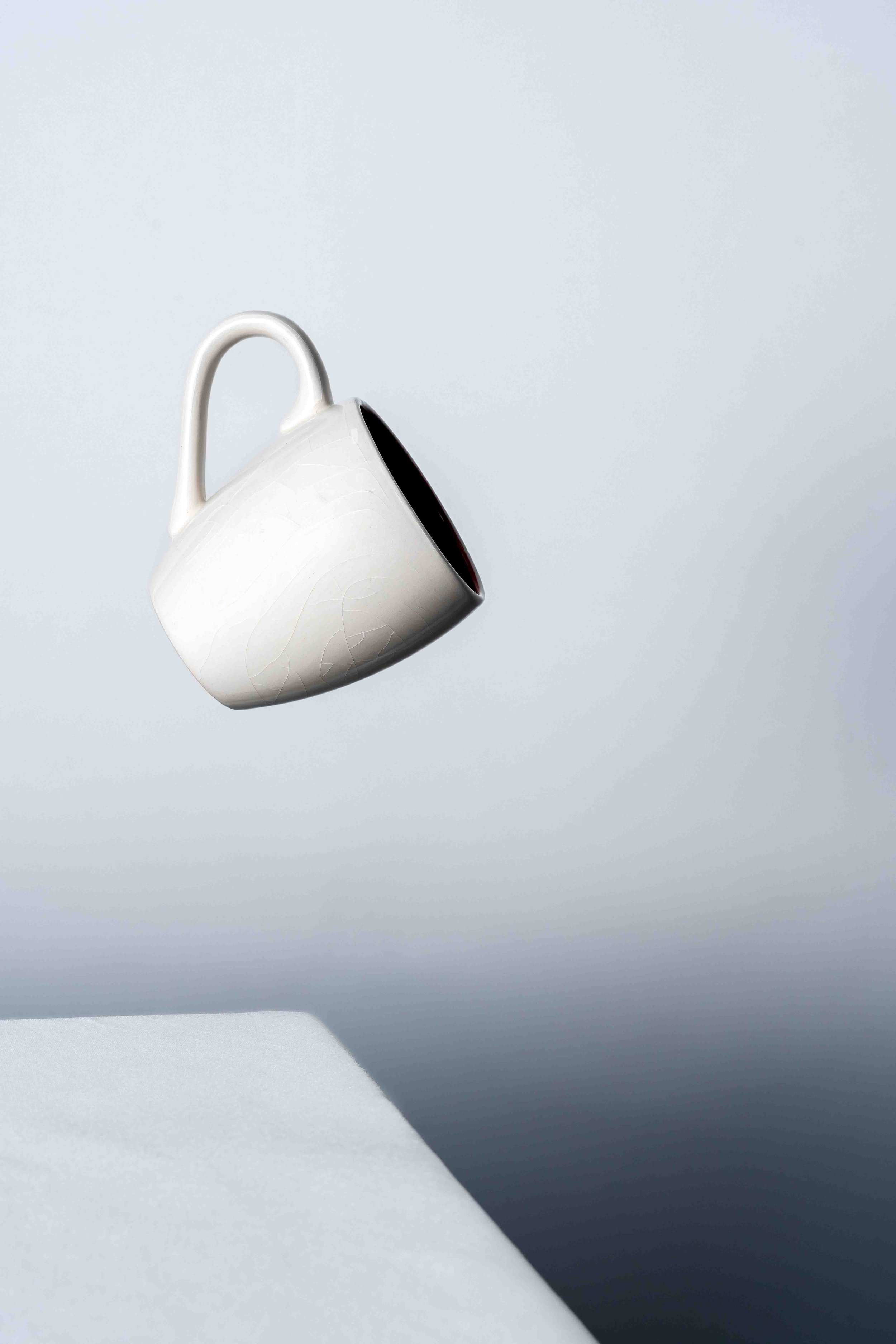 Photographie de nature morte minimaliste mettant en scène une tasse blanche en suspension. Une image épurée qui explore la lumière, la matière et l’équilibre dans une esthétique contemporaine et haut de gamme.