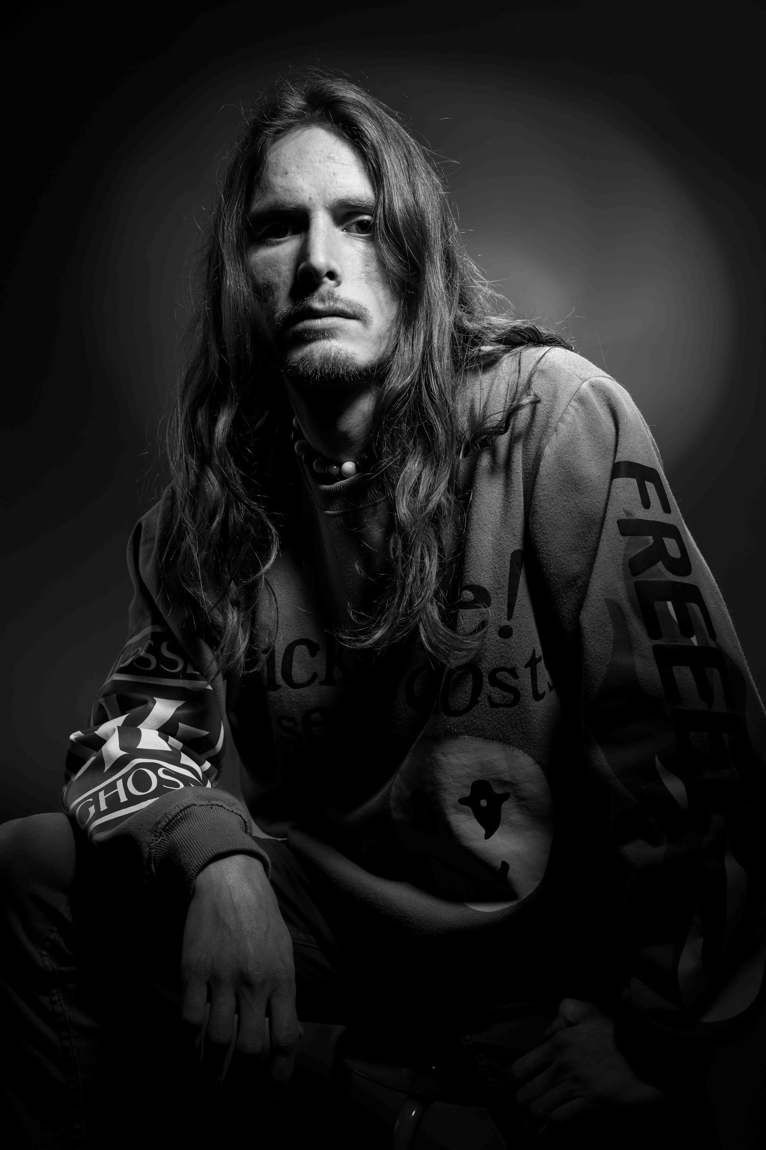 Portrait noir et blanc en studio d’un homme au regard direct. Éclairage contrasté et fond sombre créant une atmosphère intense et épurée.