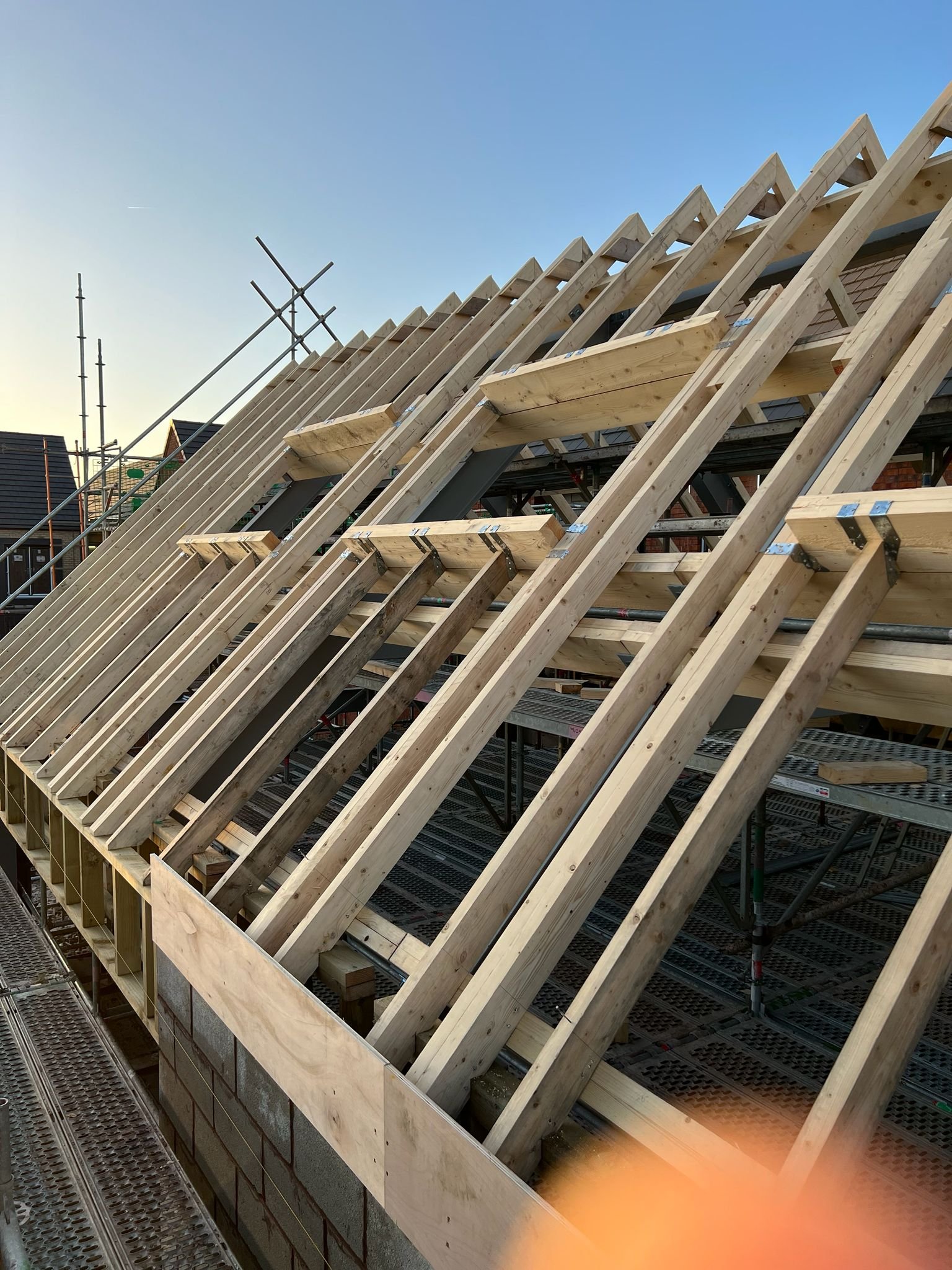 Construction site with wooden roof trusses being installed on a building under construction.