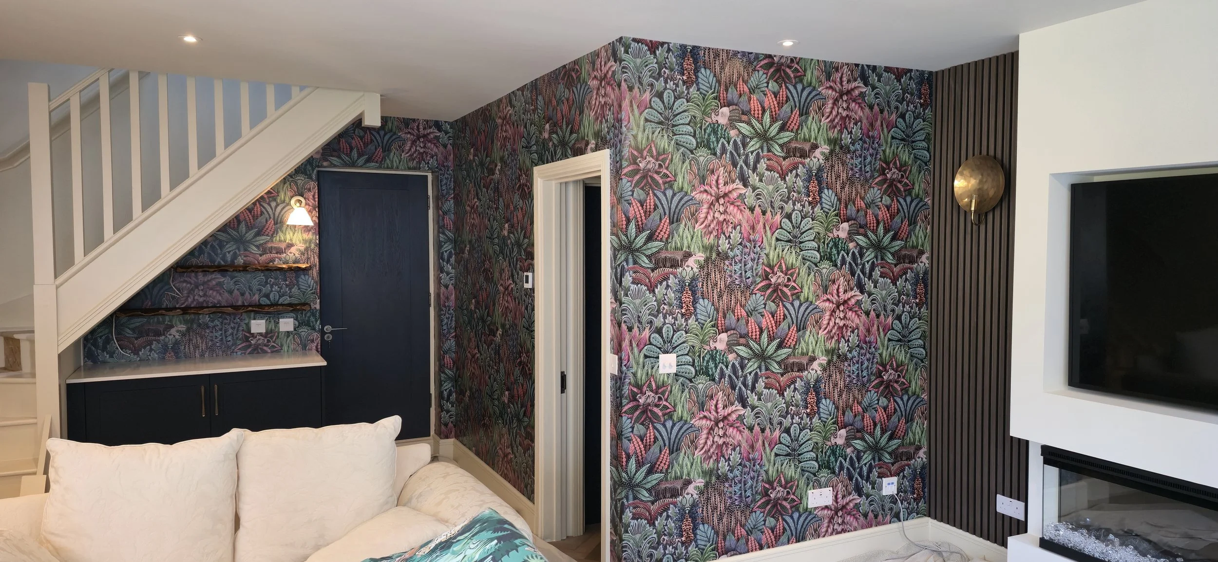 Statement jungle wallpaper installation. Feature wall decoration with integrated media unit and seamless pattern matching around stairs.