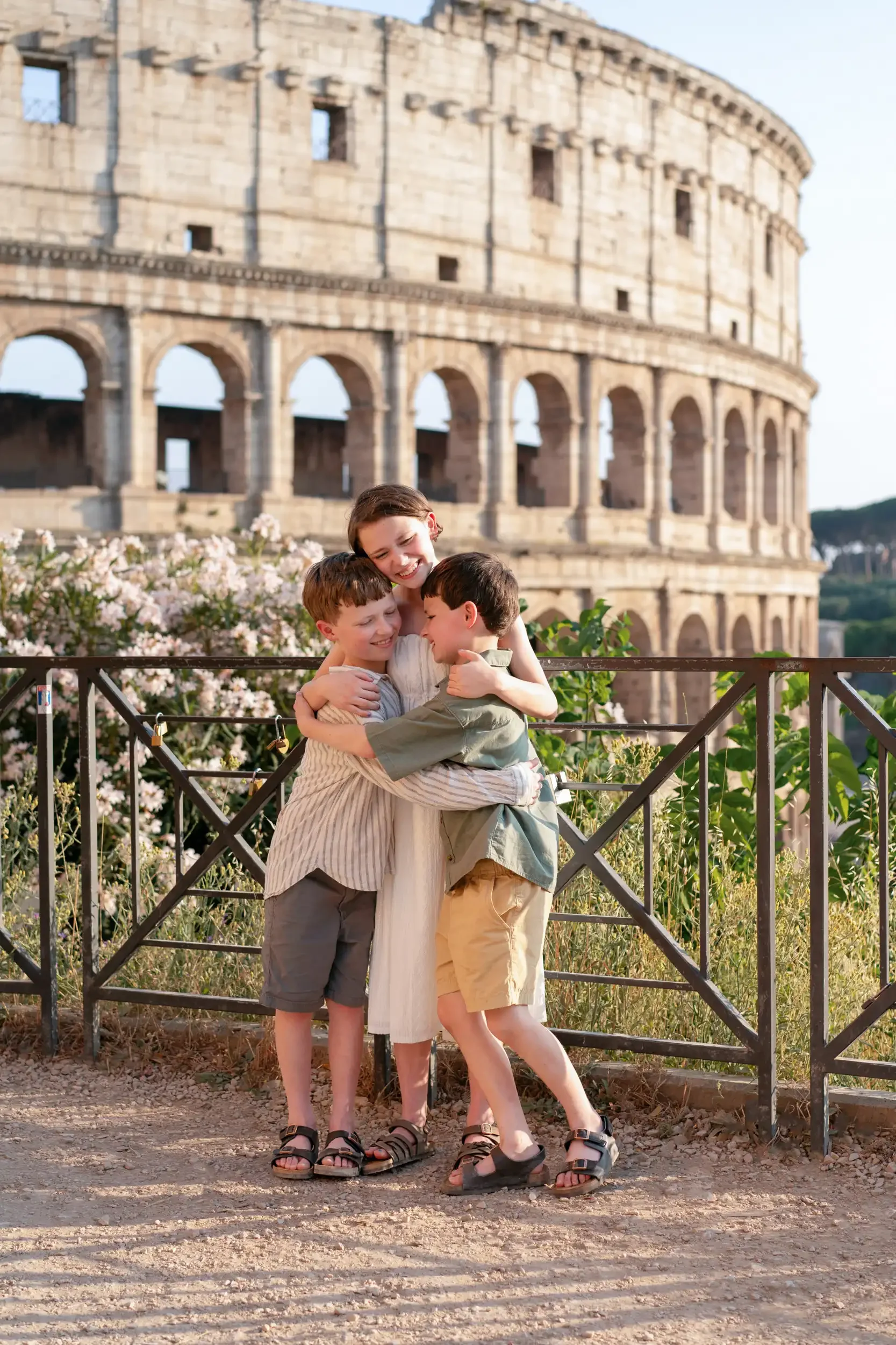 A woman hugging three children in front of the Colosseum in Rome, Italy, during daytime.