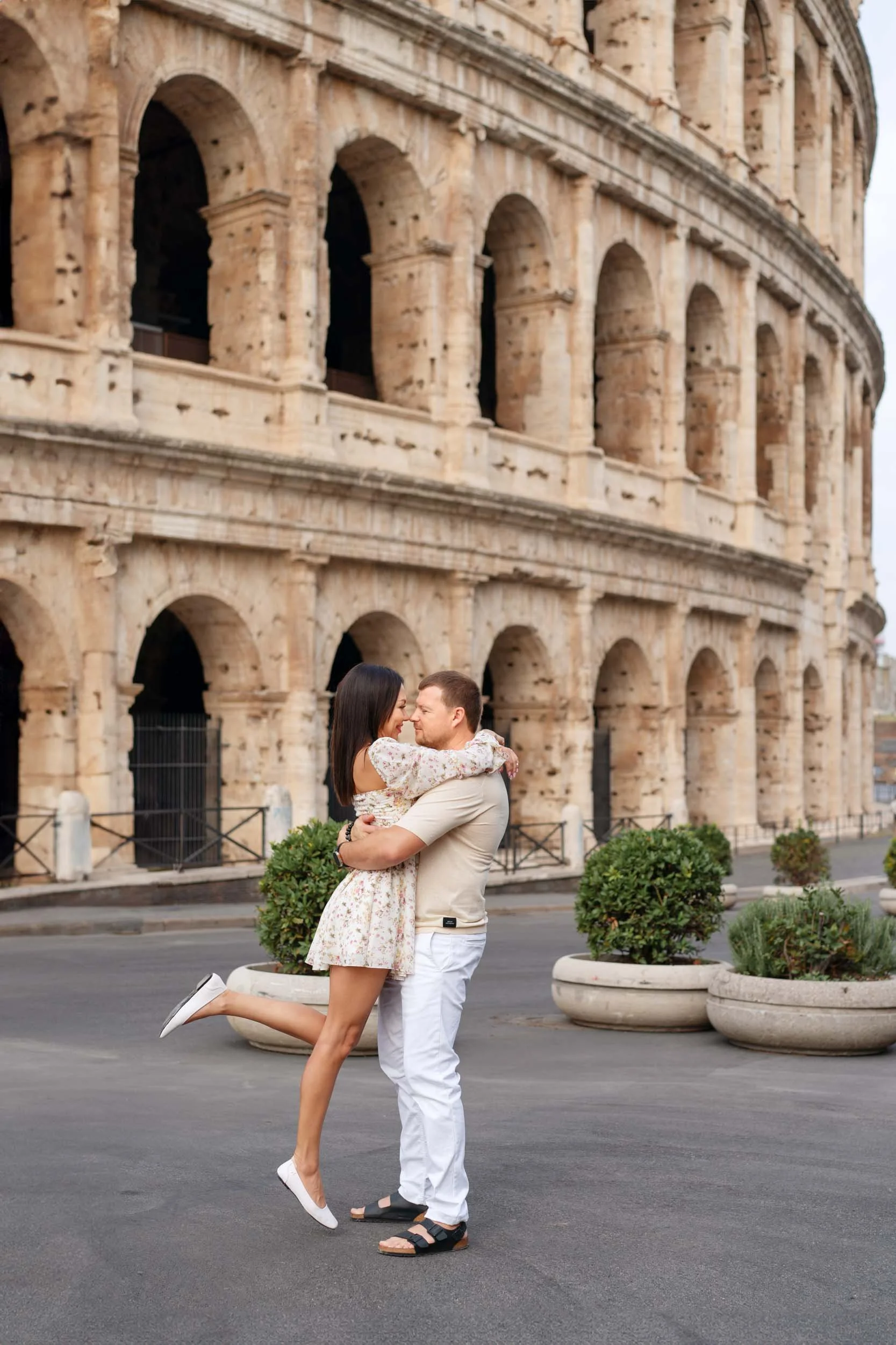 A couple embracing romantically in front of the Roman Colosseum.