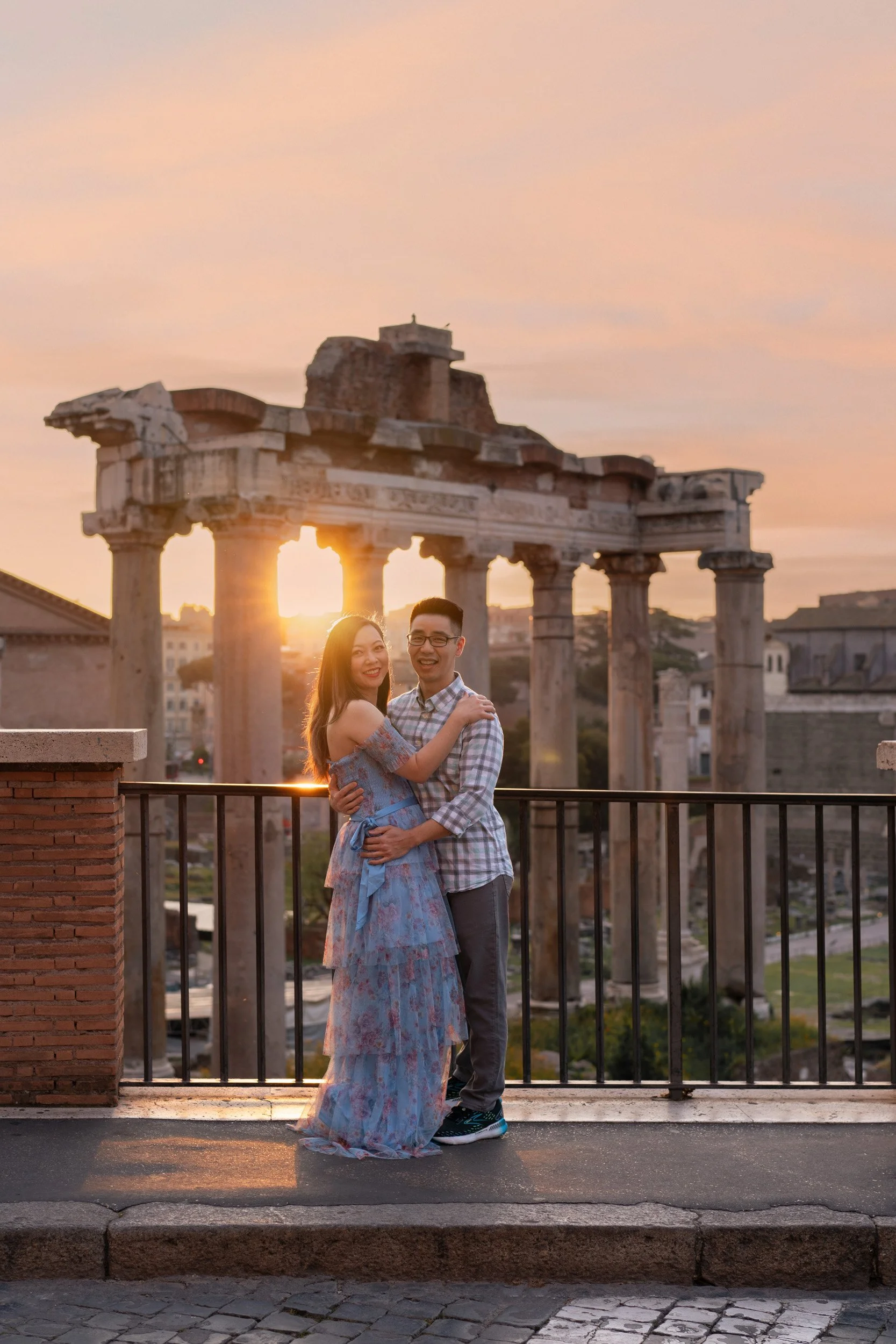 A happy couple embracing in front of ancient ruins during sunset.