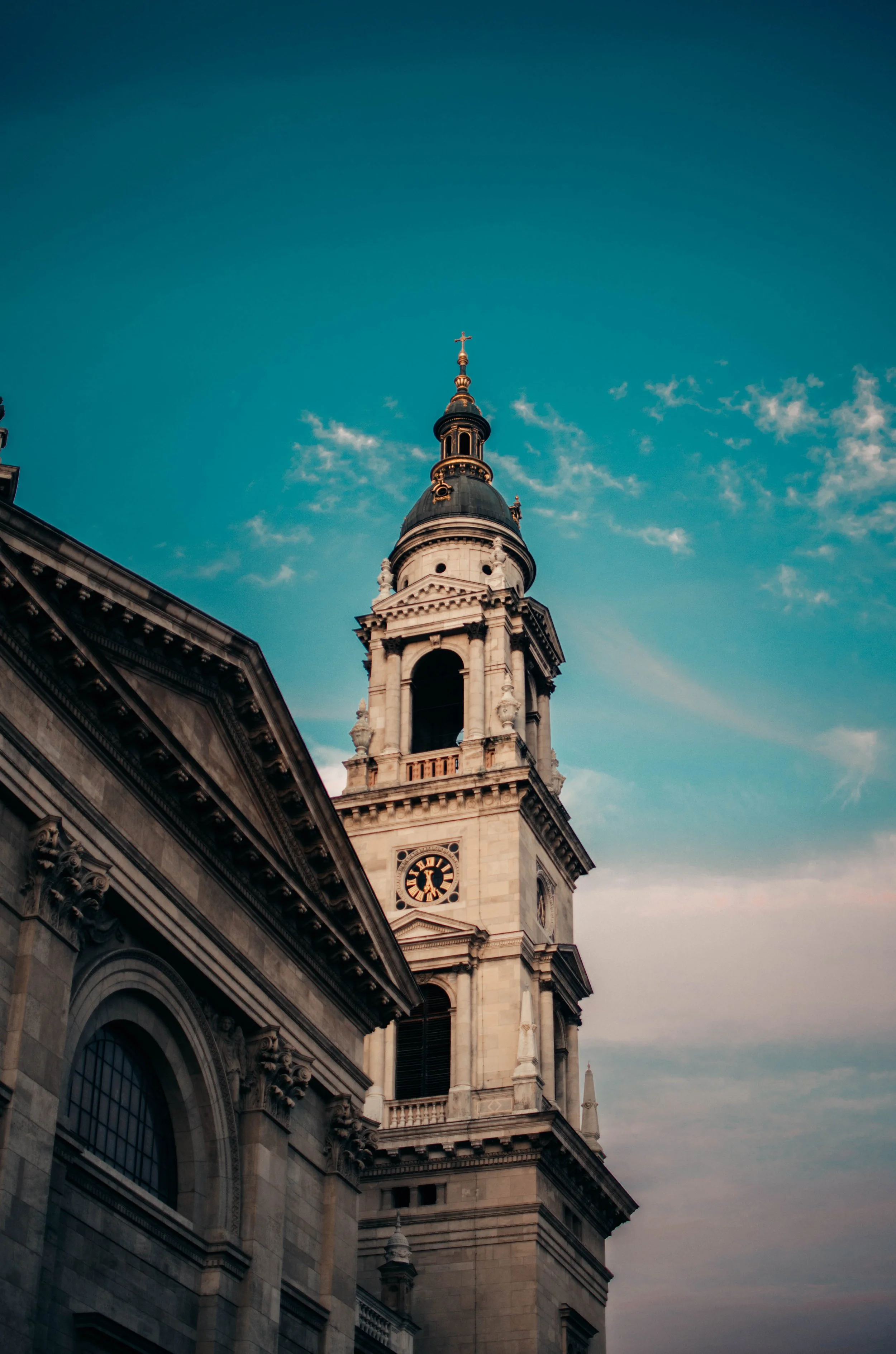 Close-up of a historic church or cathedral steeple against a clear blue sky with wispy clouds.