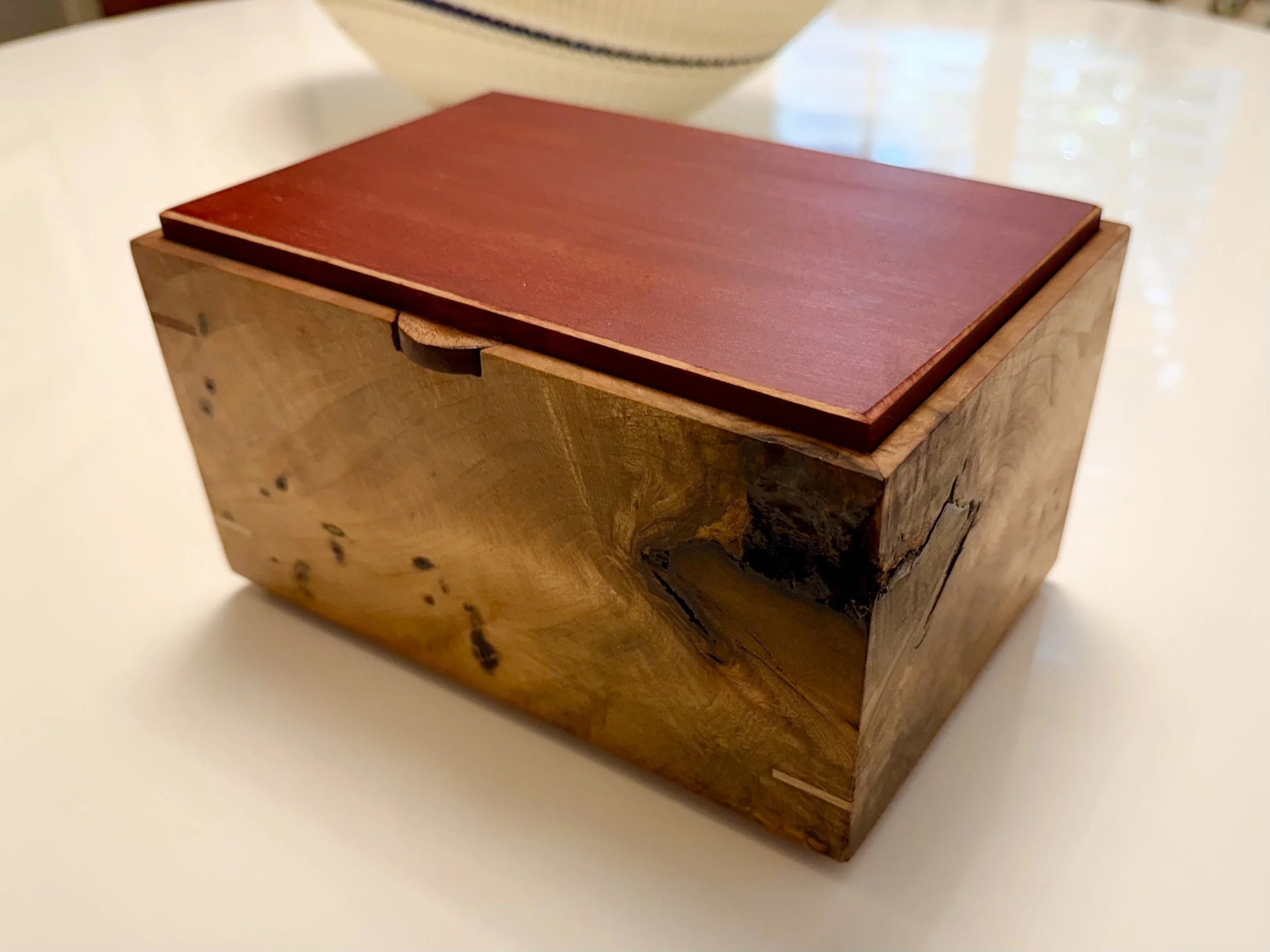 A wooden box with a red lid on a white surface.