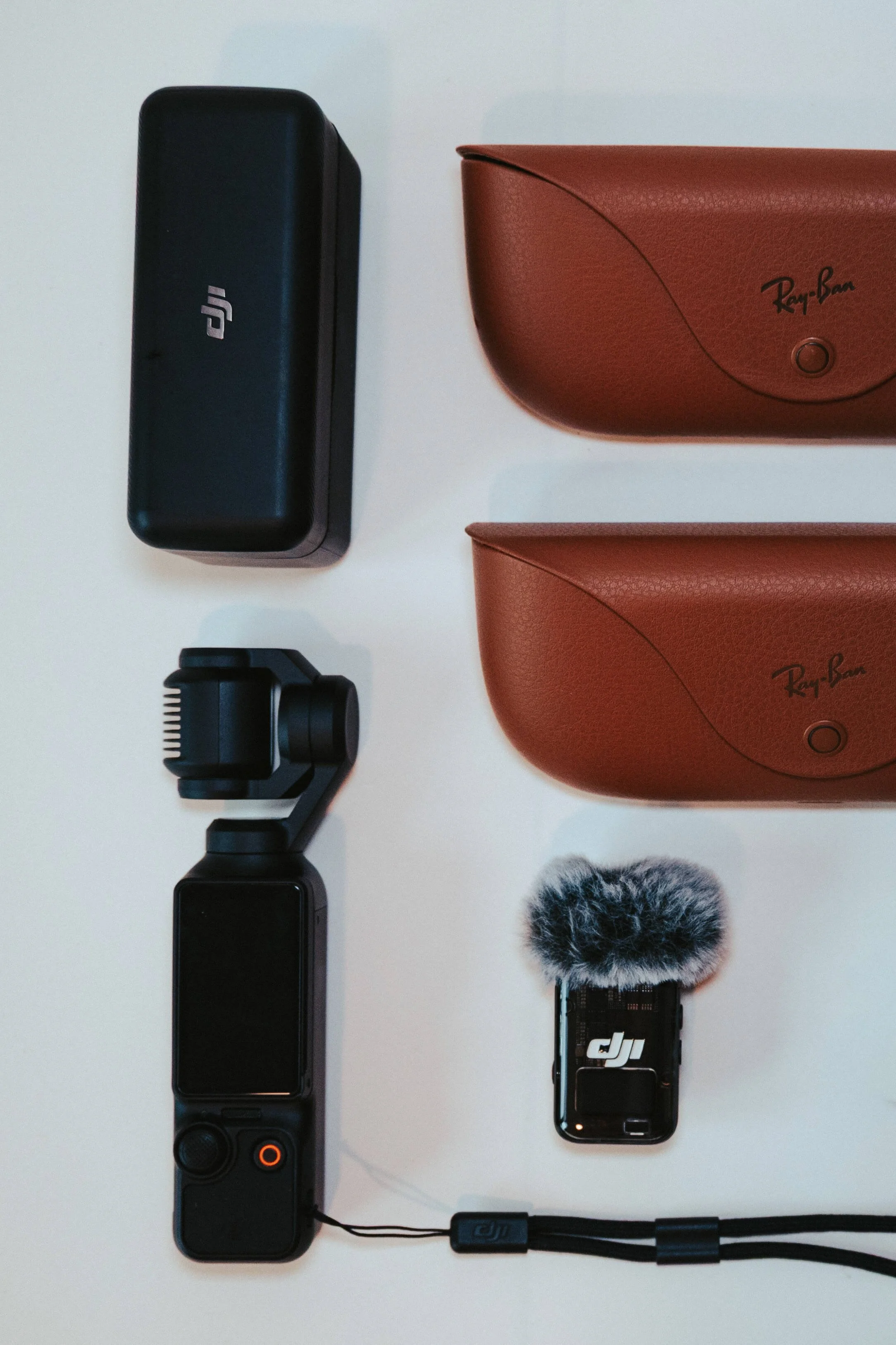 Content creator gear including DJI camera, microphone, sunglasses cases, and accessories used for social media video production.